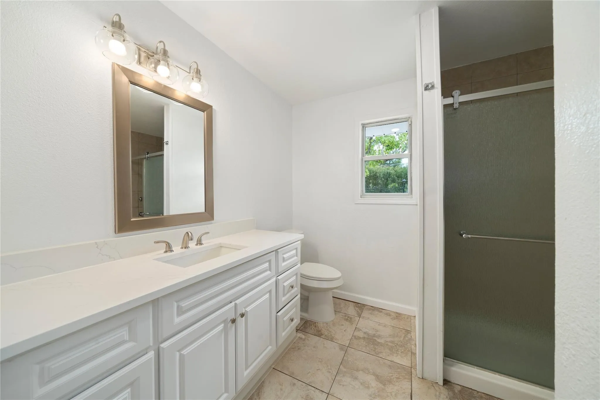 Bathroom featuring a white vanity with extensive storage, a white countertop, an undermount sink, and a brushed nickel faucet