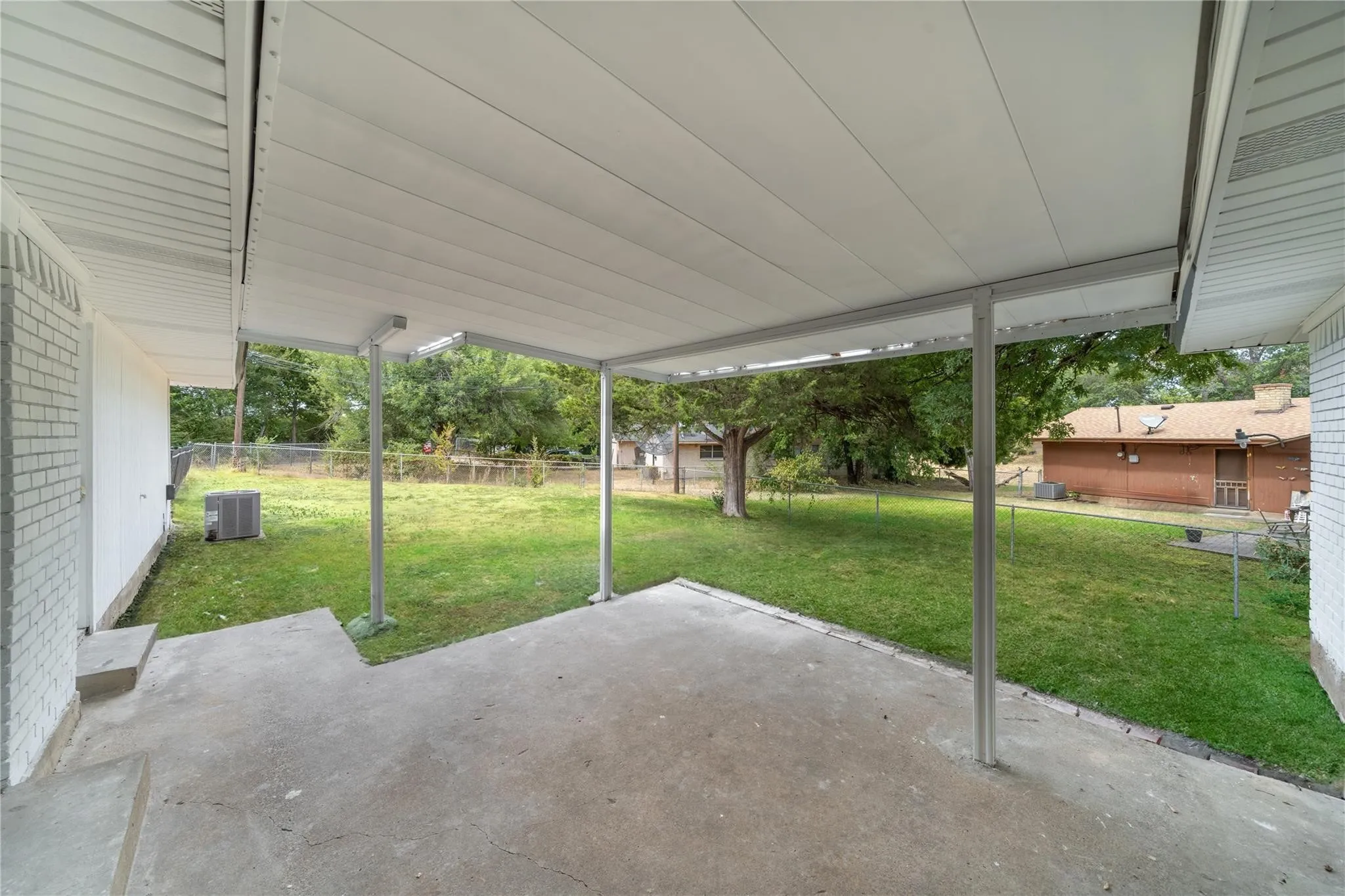 Covered concrete patio with a white metal awning