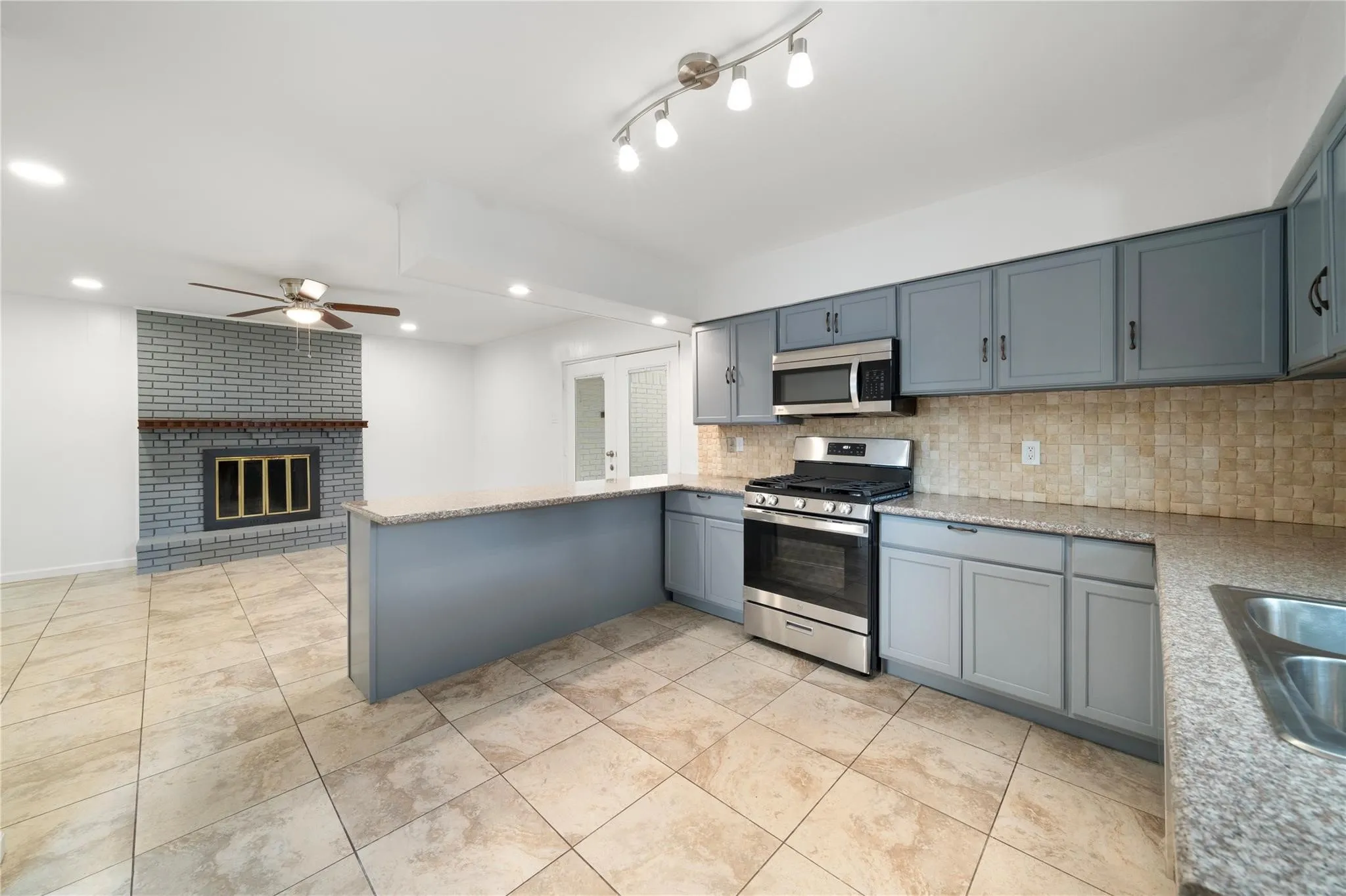 Kitchen featuring gray cabinetry, stainless steel appliances, granite countertops, and a tiled backsplash
