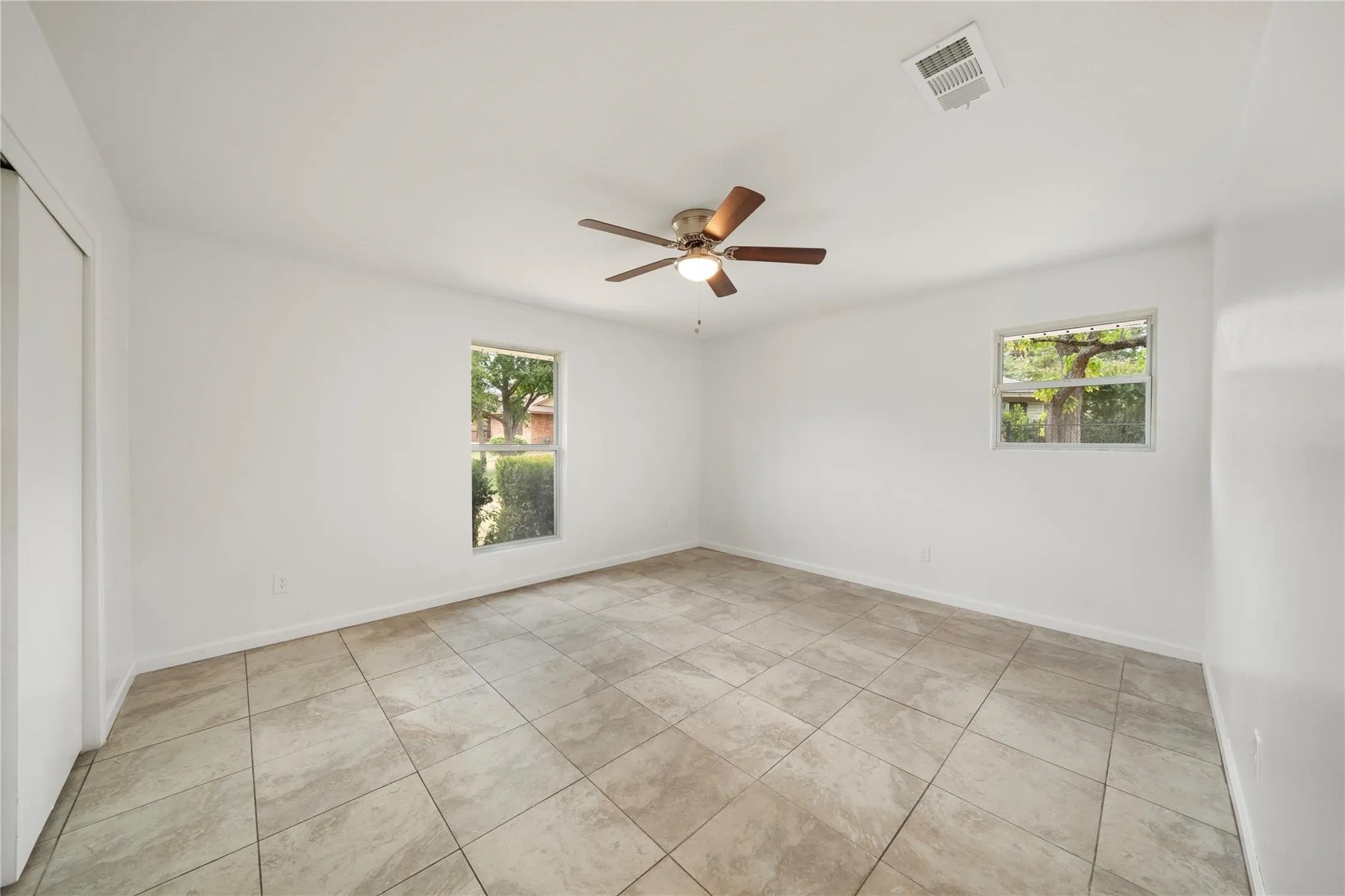 Spacious room featuring neutral-toned tile flooring and white walls