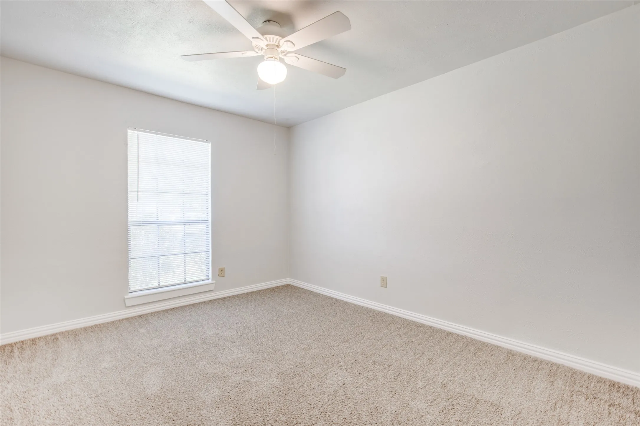Bedroom featuring light-toned carpeting, a window with horizontal blinds, and a ceiling fan with integrated lighting