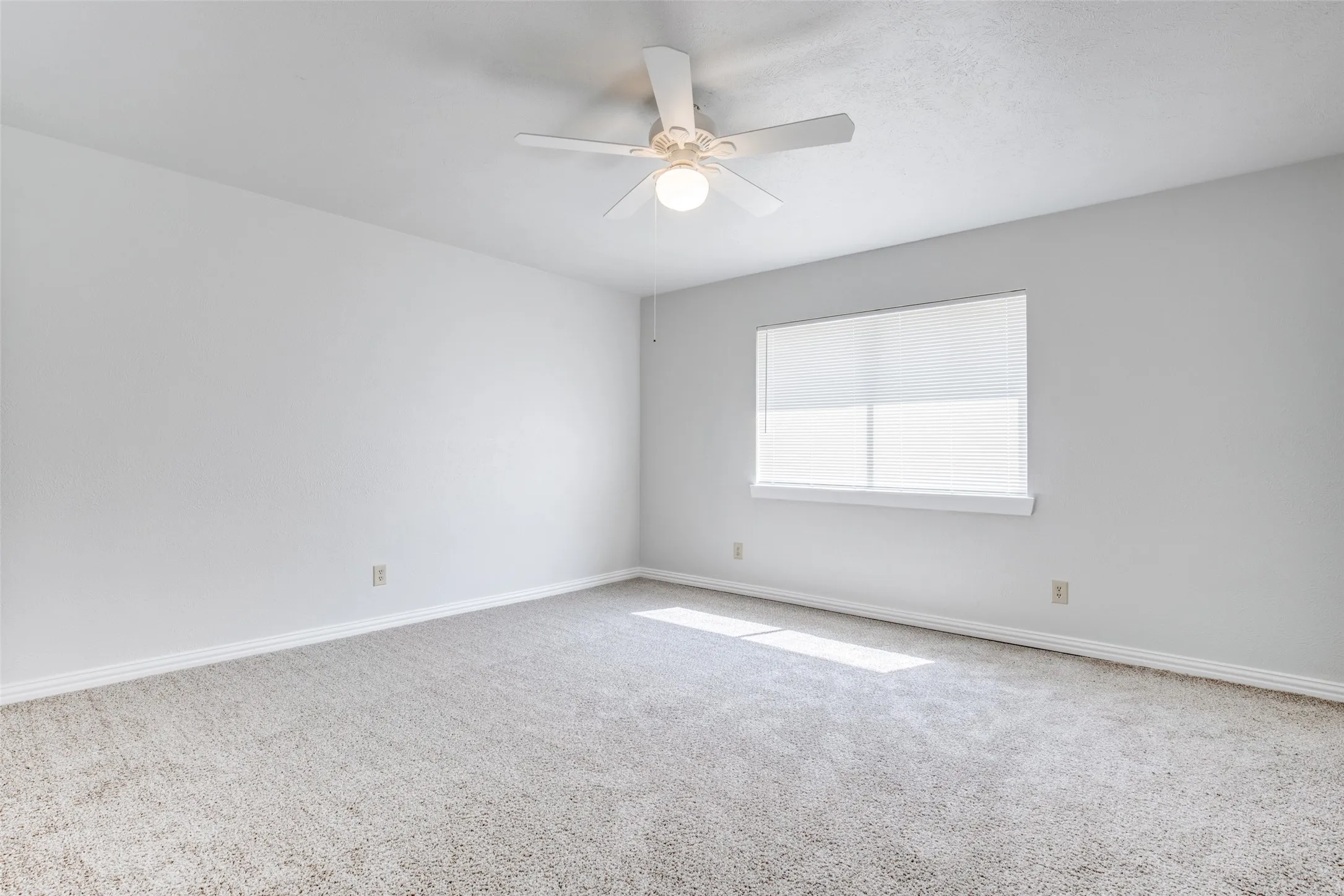 Carpeted interior space featuring light-toned walls and a ceiling fan with integrated lighting