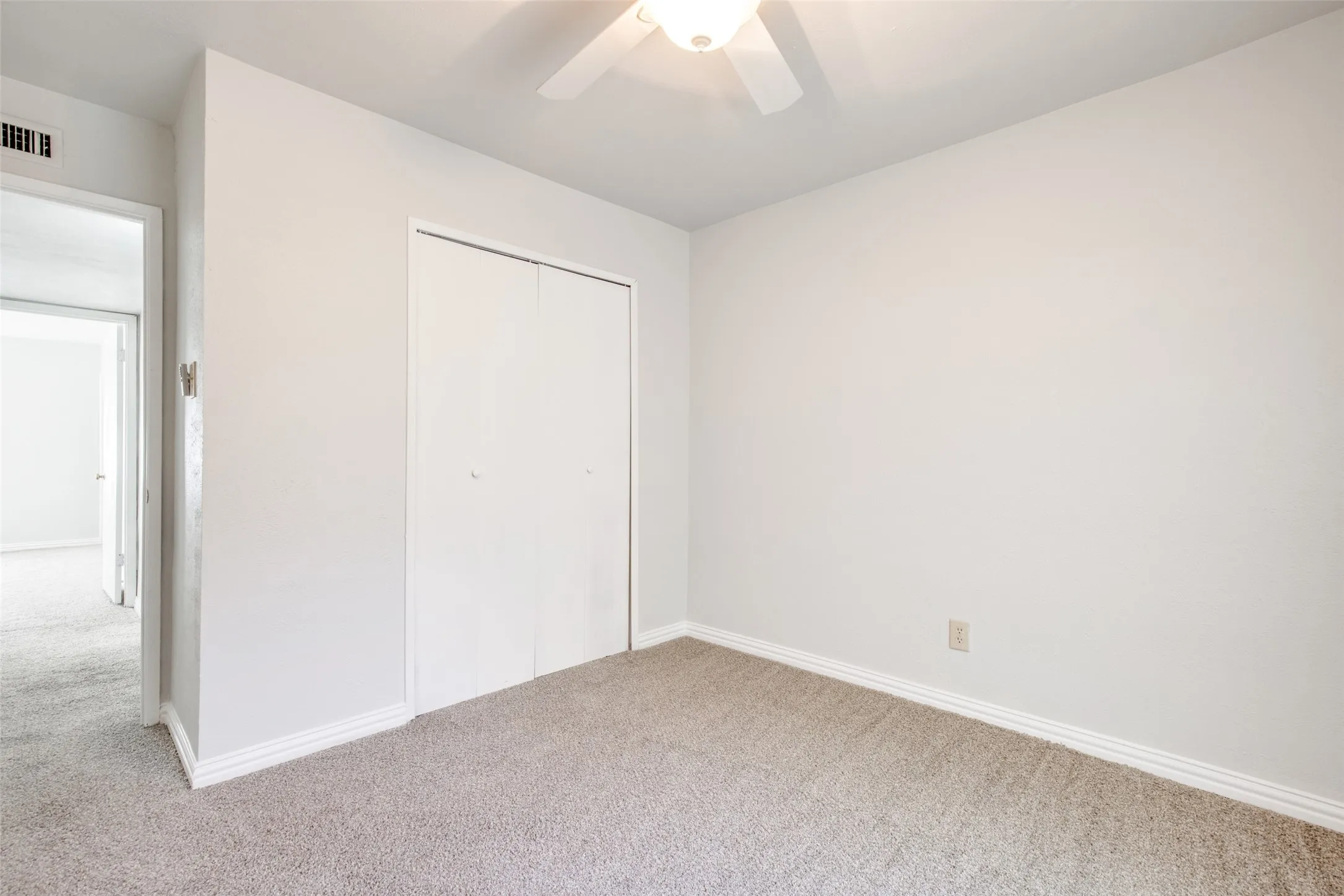 Carpeted room featuring a ceiling fan, baseboard molding, and a bi-fold closet