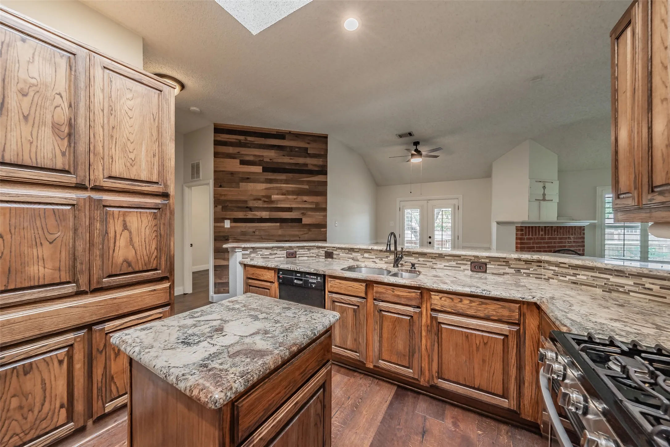 Kitchen featuring wood cabinetry, granite-style countertops, mosaic tile backsplash, and a central island