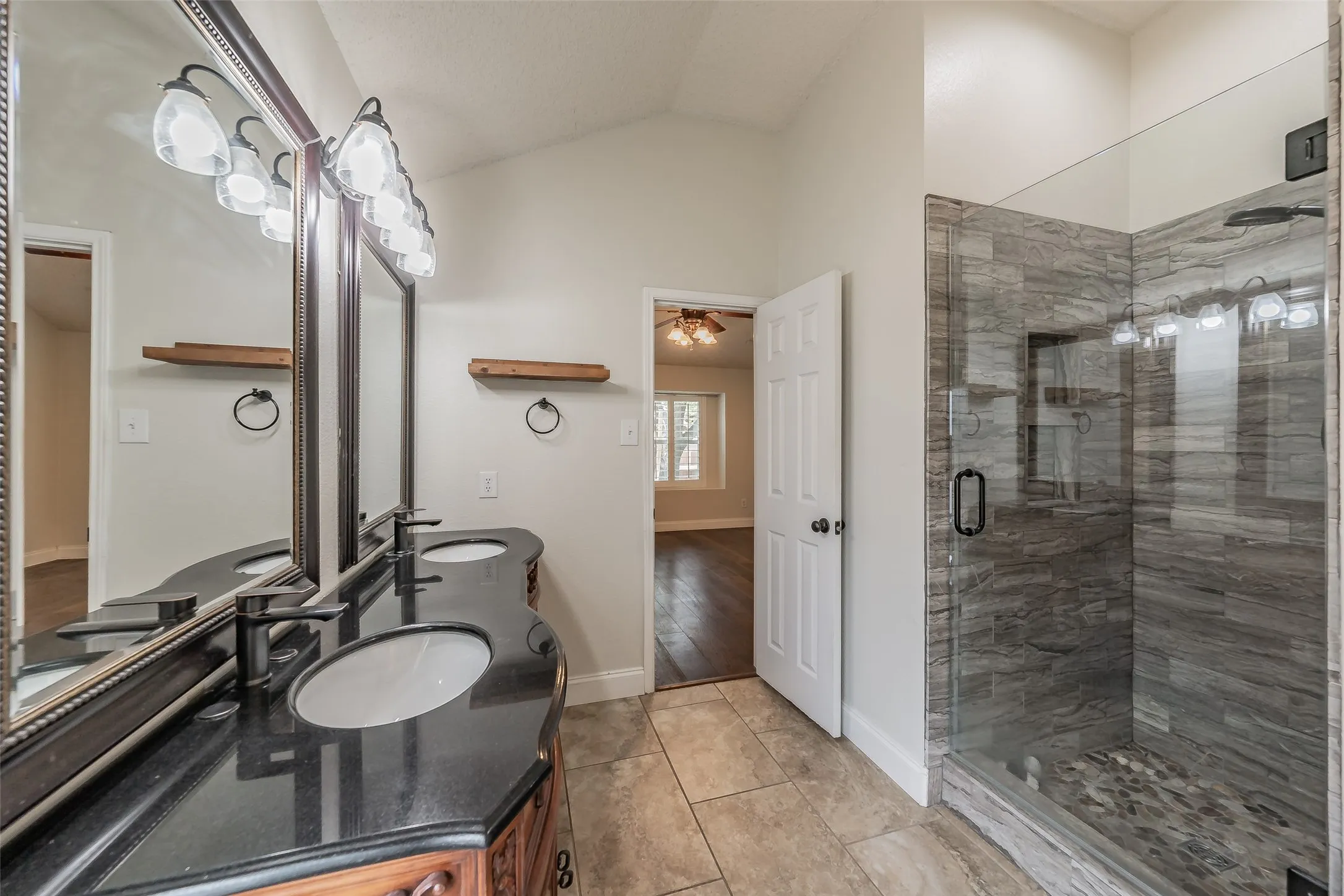 Bathroom featuring a double vanity with dark countertops, dual undermount sinks, and contemporary black fixtures