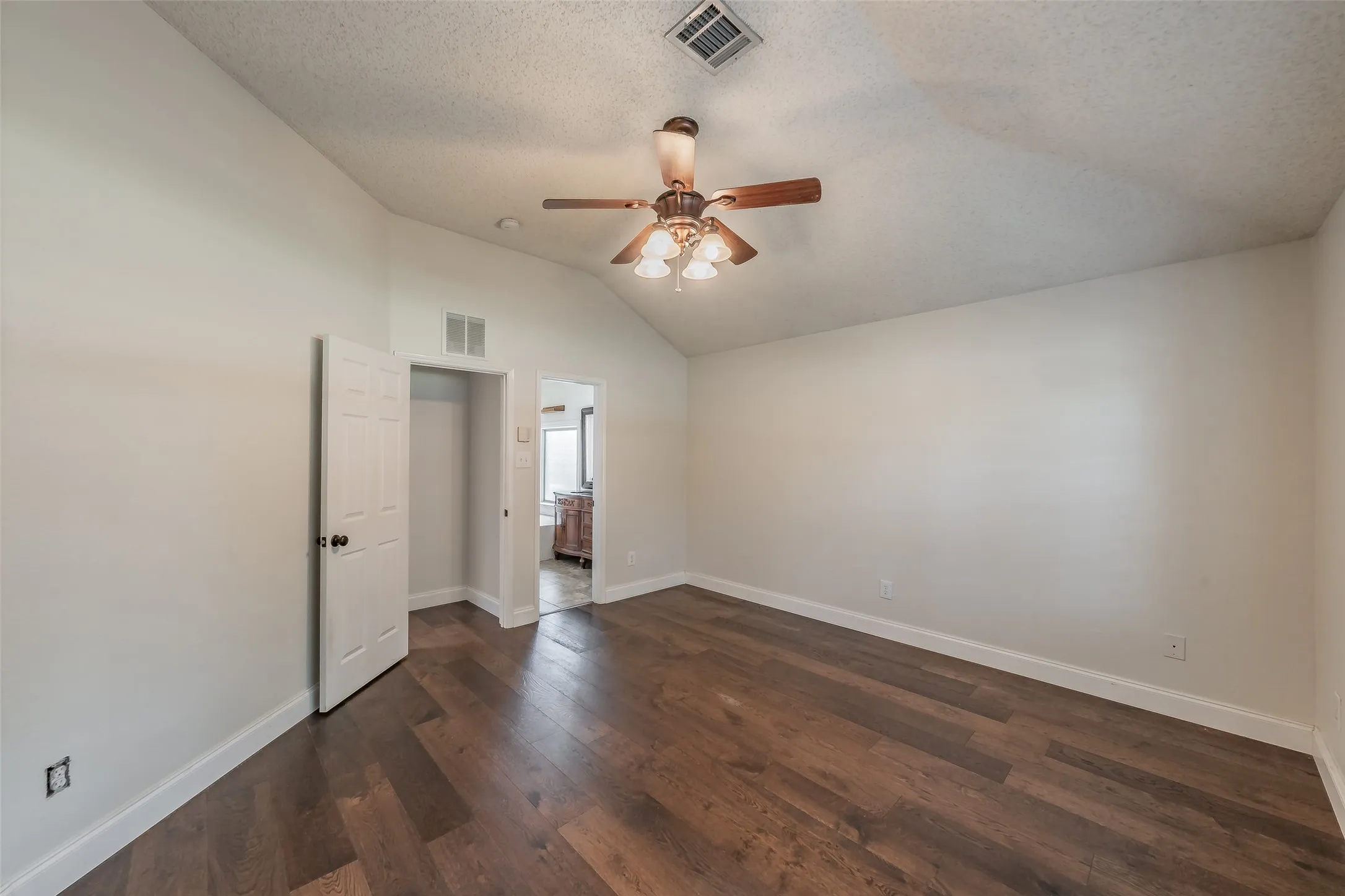 Spacious interior featuring wood-finish flooring, vaulted ceilings, and a ceiling fan