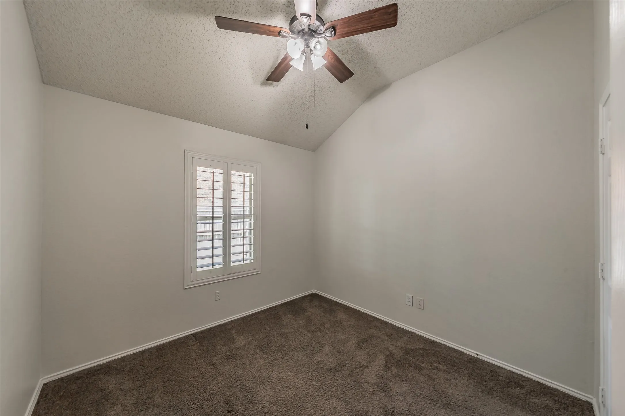 Interior room featuring a vaulted ceiling and textured ceiling finish