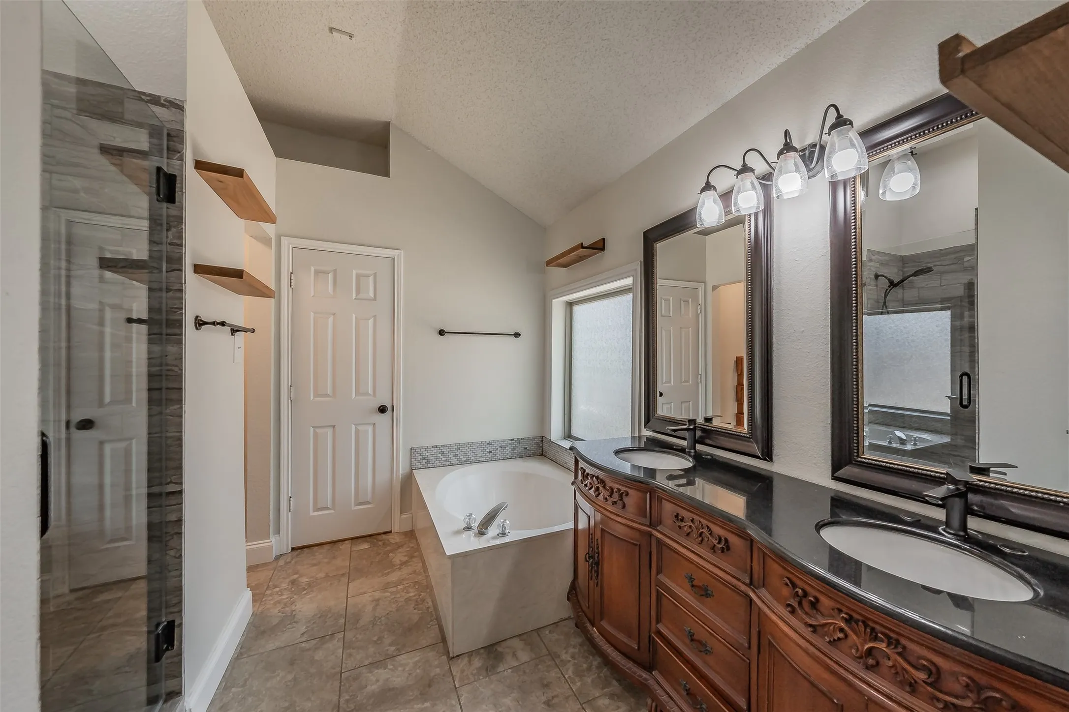 Bathroom featuring a dual vanity with ornate wood cabinetry, black countertops, and undermount sinks