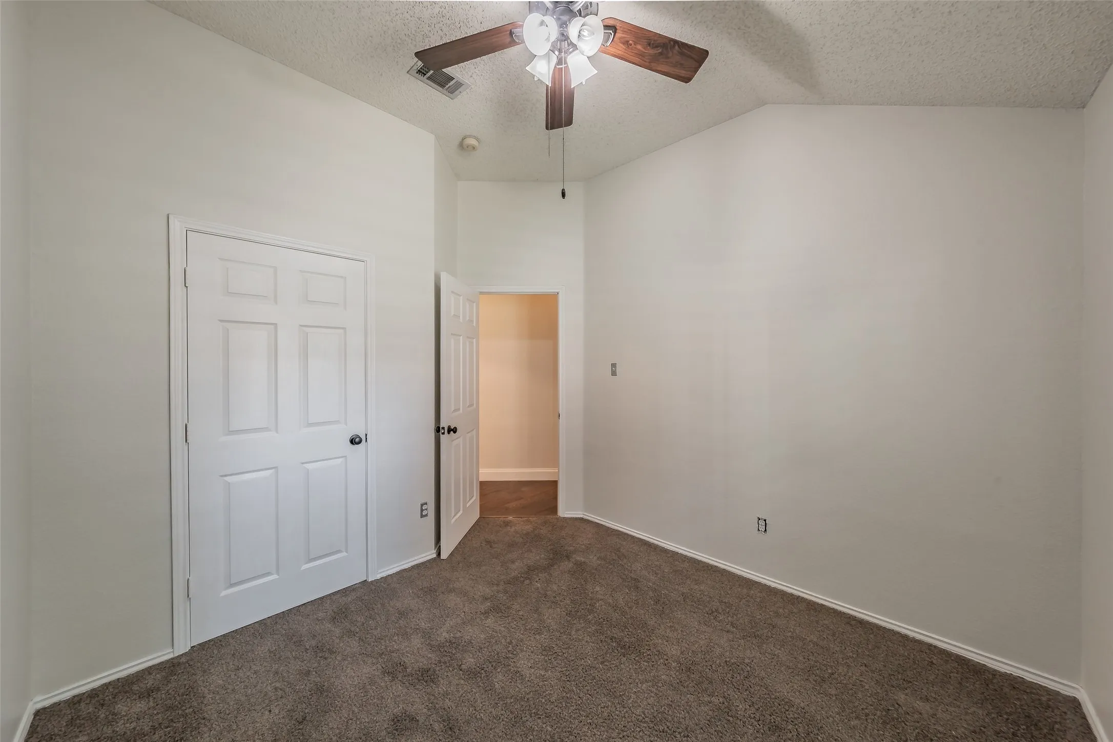 Room featuring vaulted ceilings, neutral wall tones, and plush brown carpeting