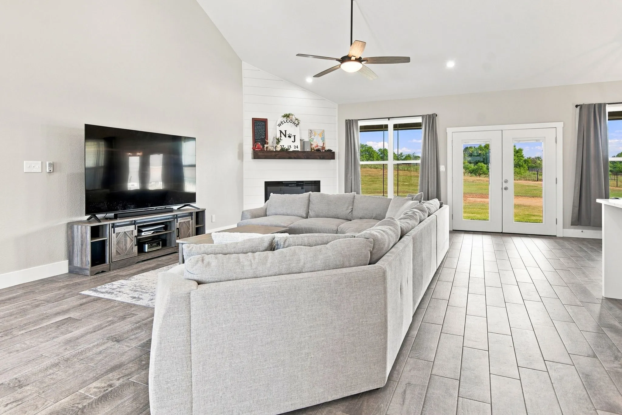 Spacious living area featuring high vaulted ceilings, light-toned walls, and wood-finish flooring