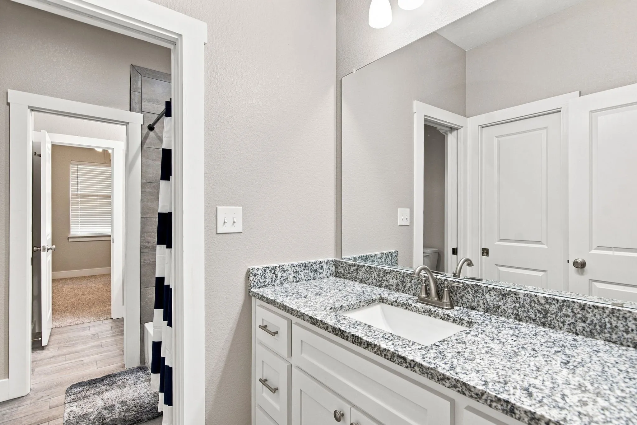 Bathroom vanity featuring a speckled countertop, undermount sink, and brushed nickel faucet