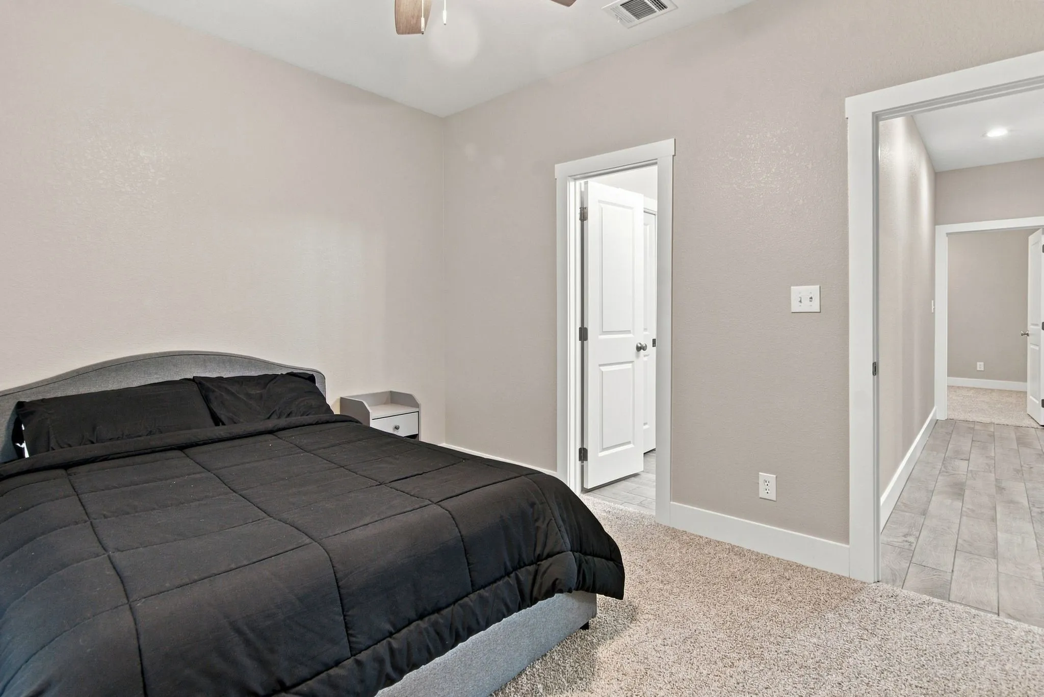 Neutral-toned bedroom featuring light textured walls and light carpet flooring