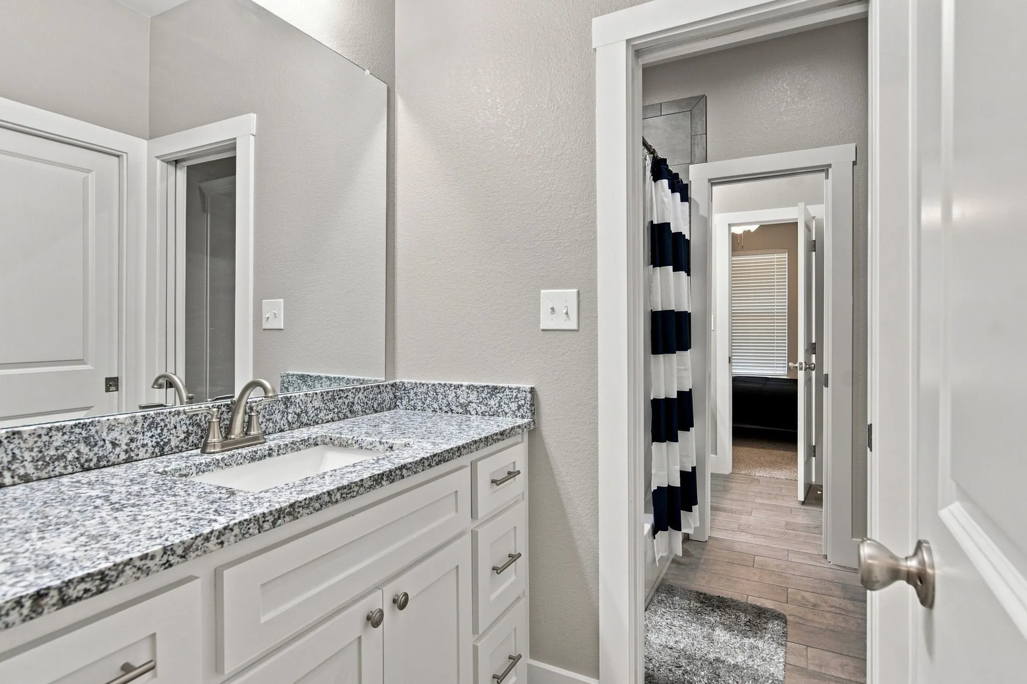 Bathroom vanity featuring white cabinetry, a rectangular undermount sink, granite countertop, and brushed nickel faucet