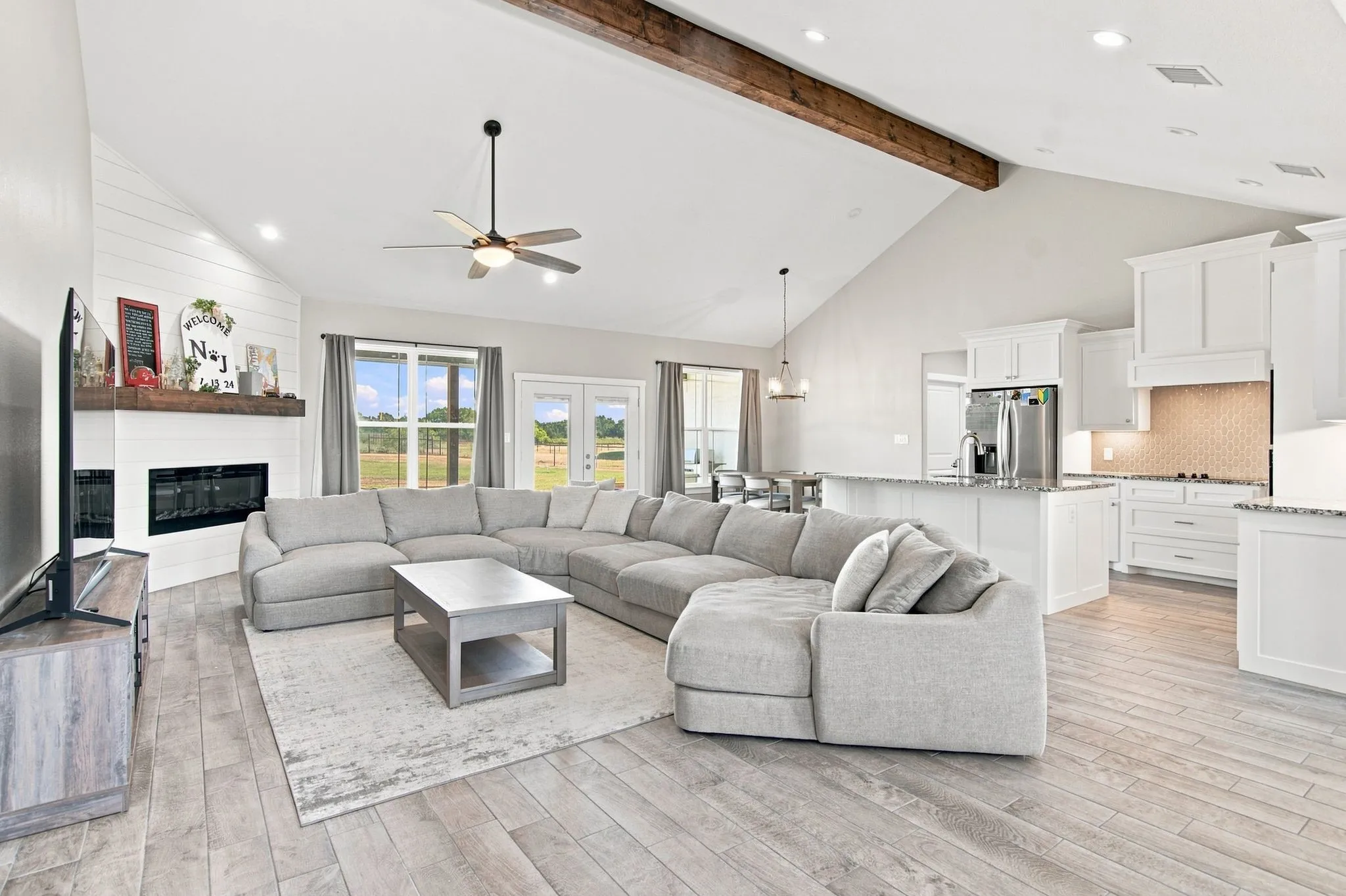 Spacious living area featuring a vaulted ceiling with a rustic wood beam accent and recessed lighting