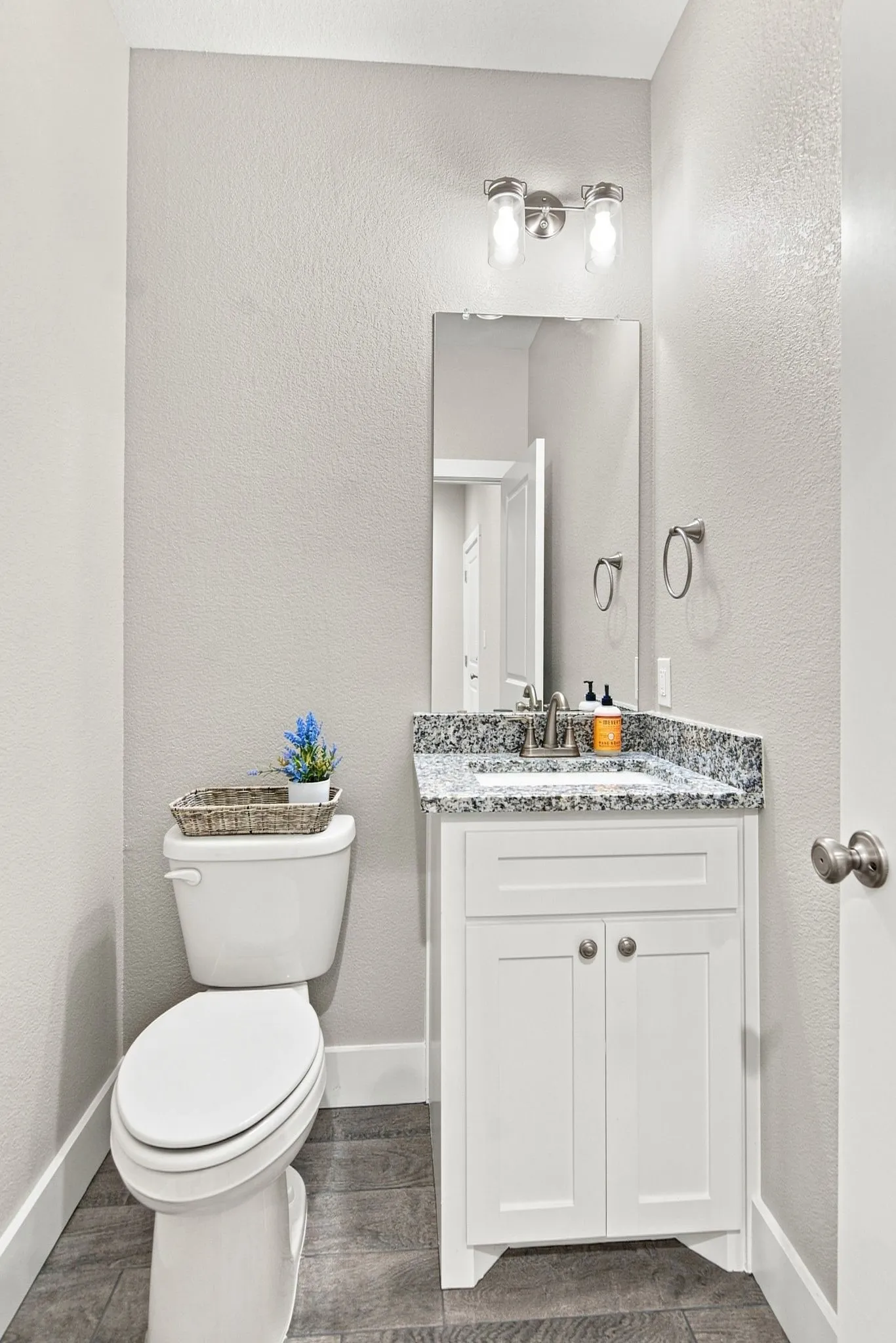 Bathroom featuring a white vanity with granite countertop, integrated sink, and brushed nickel hardware