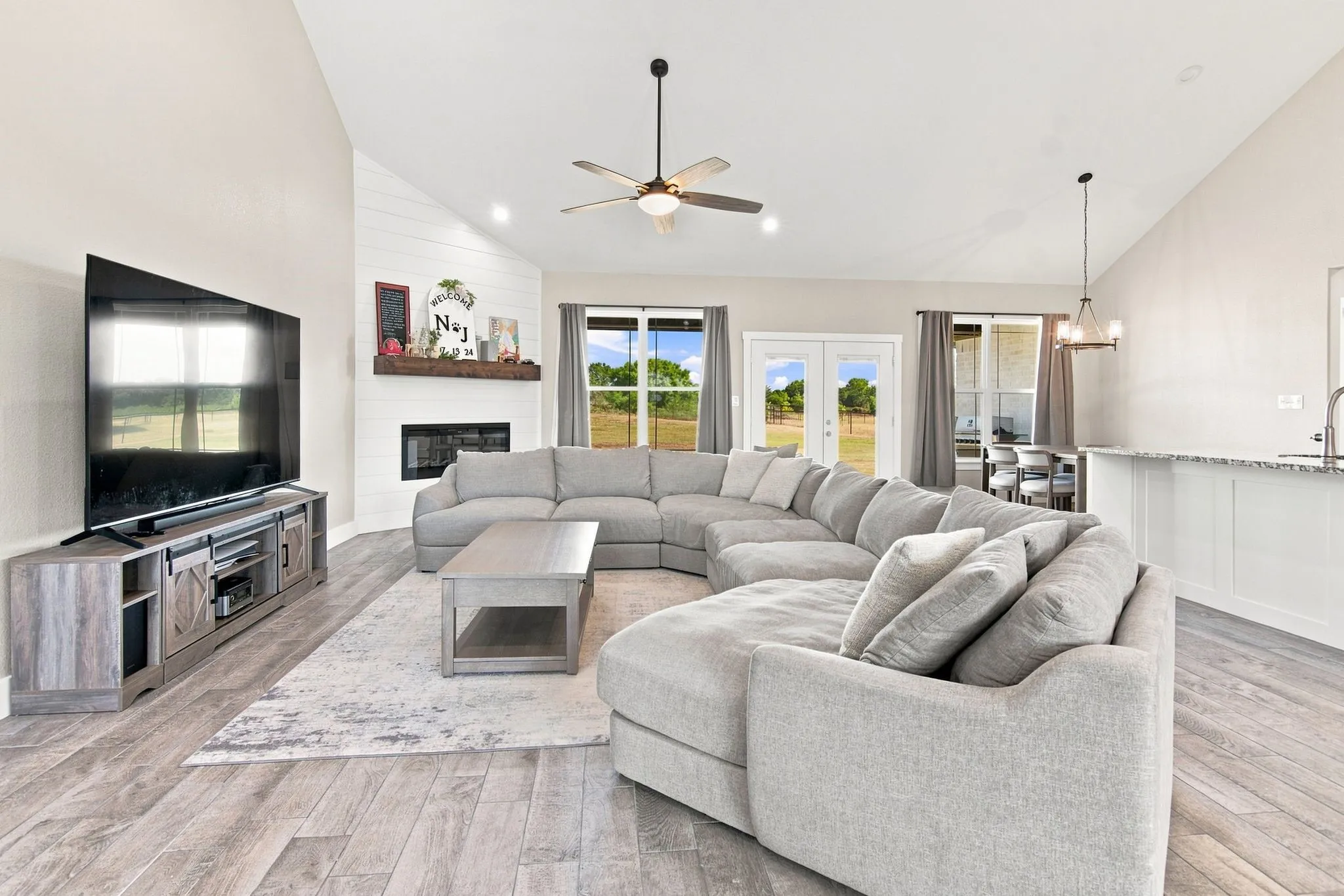 Vaulted great room featuring wood-finish flooring and a corner fireplace with a shiplap accent wall