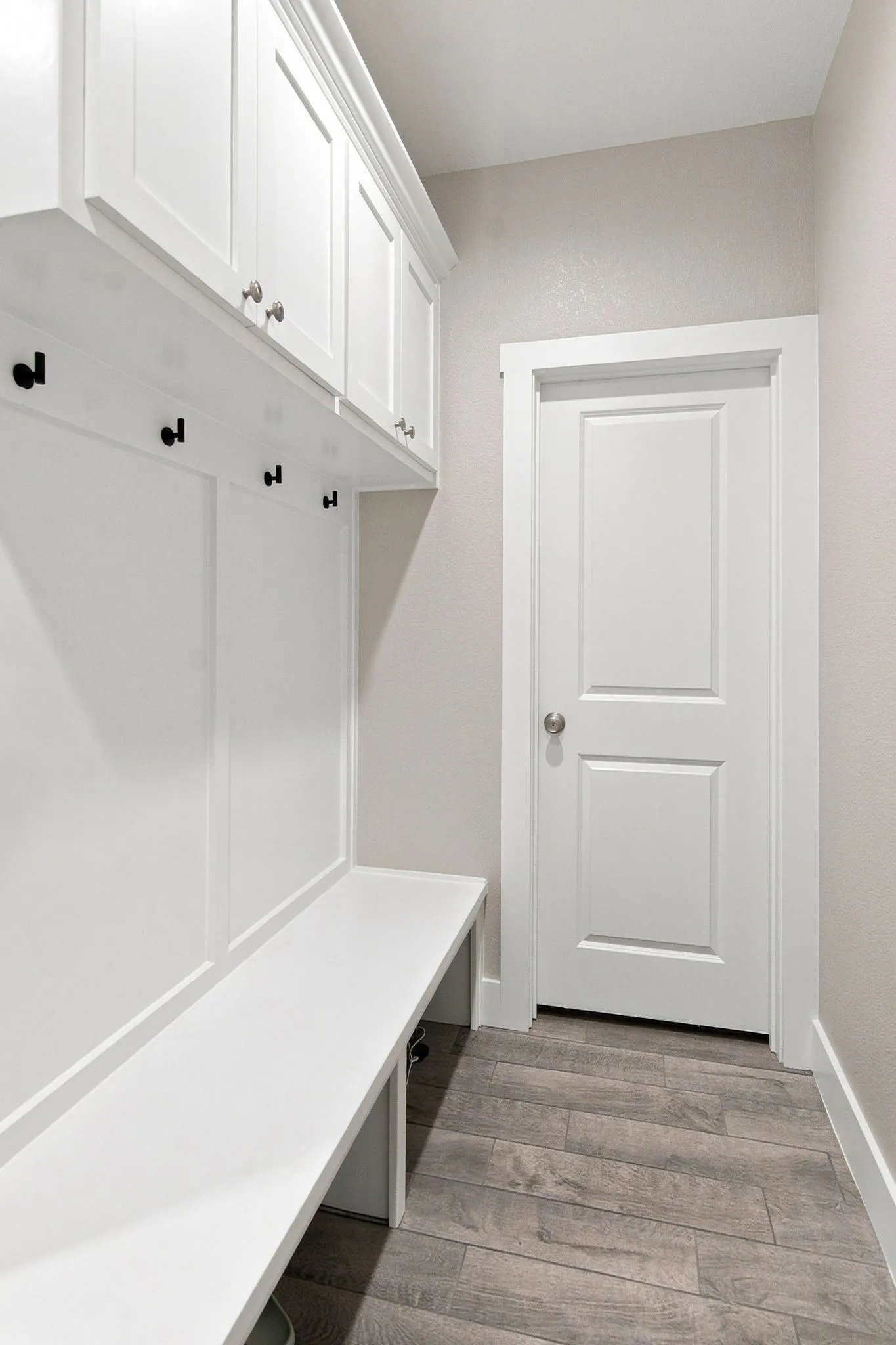 Built-in mudroom bench with upper cabinetry and integrated coat hooks