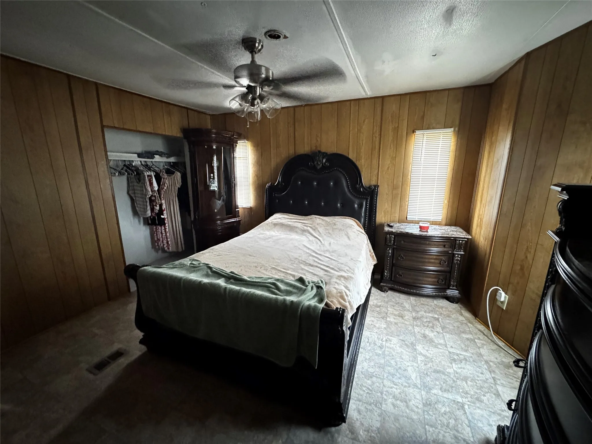 Vertical wood-finish paneling, ceiling fan with light fixture, window with blinds, and varied flooring