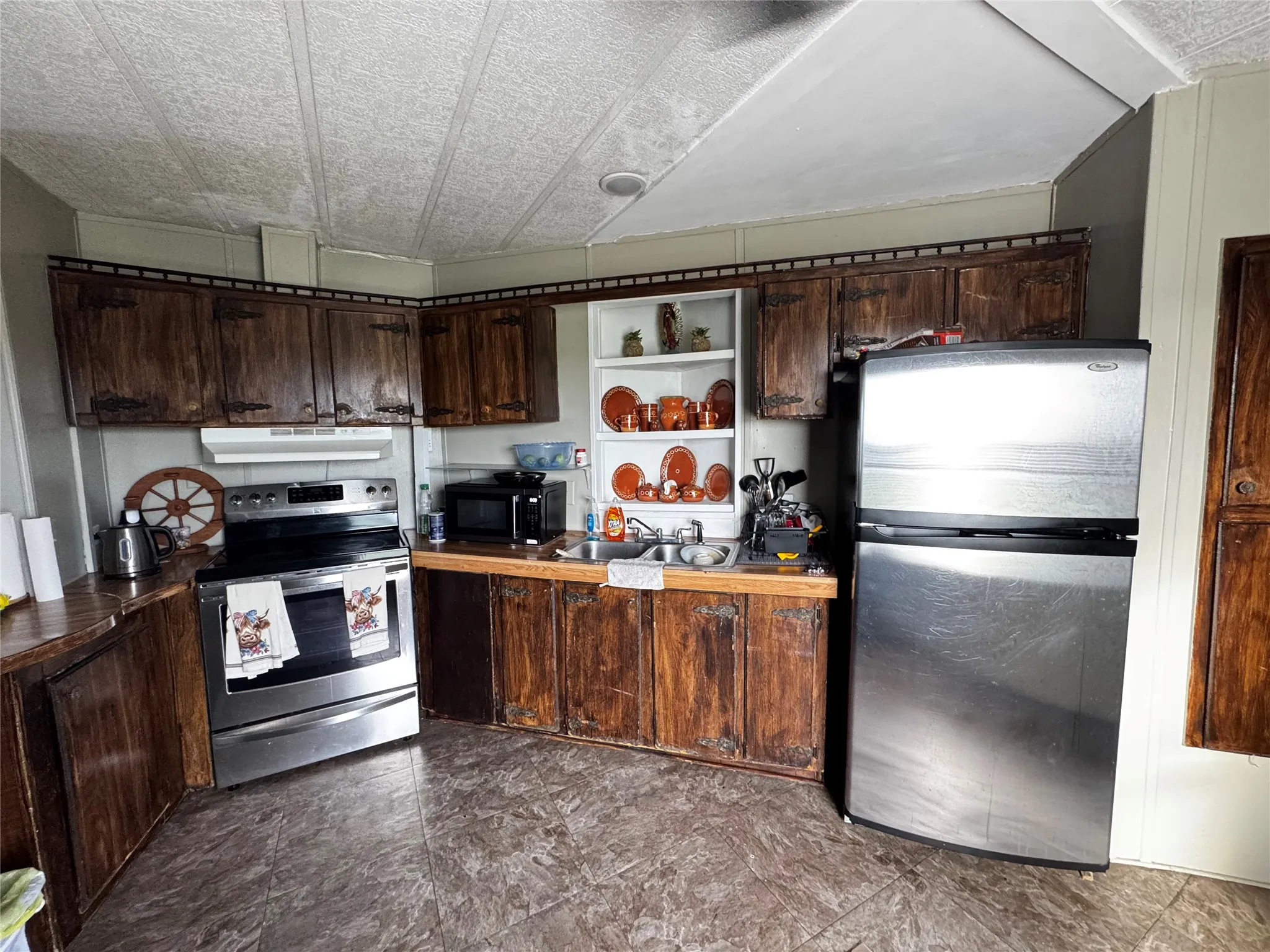 Kitchen featuring wood-finish cabinetry, built-in shelving, a stainless steel range, and a stainless steel refrigerator