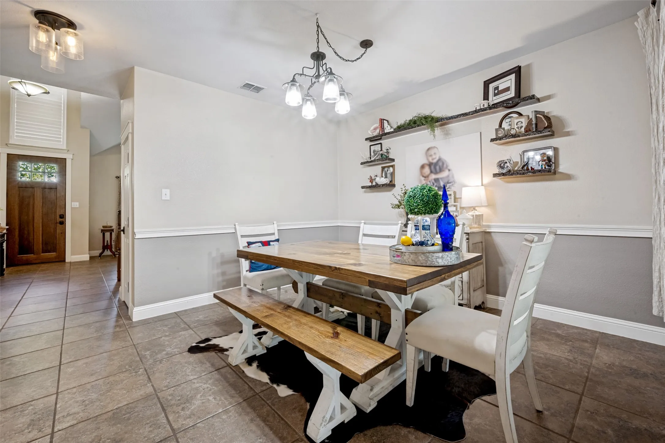 Dining area featuring tile flooring, wainscoting, and a decorative chandelier