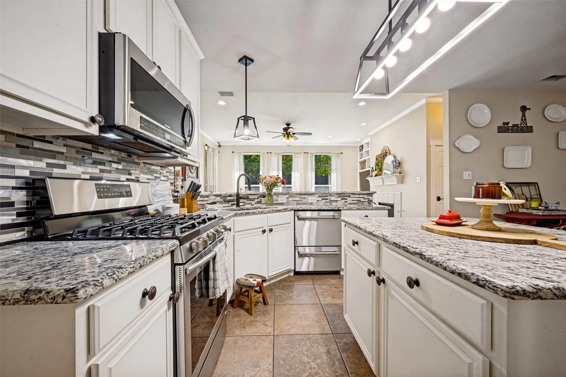 Kitchen featuring white cabinetry, stone countertops, stainless steel appliances, a tile backsplash, and tile flooring