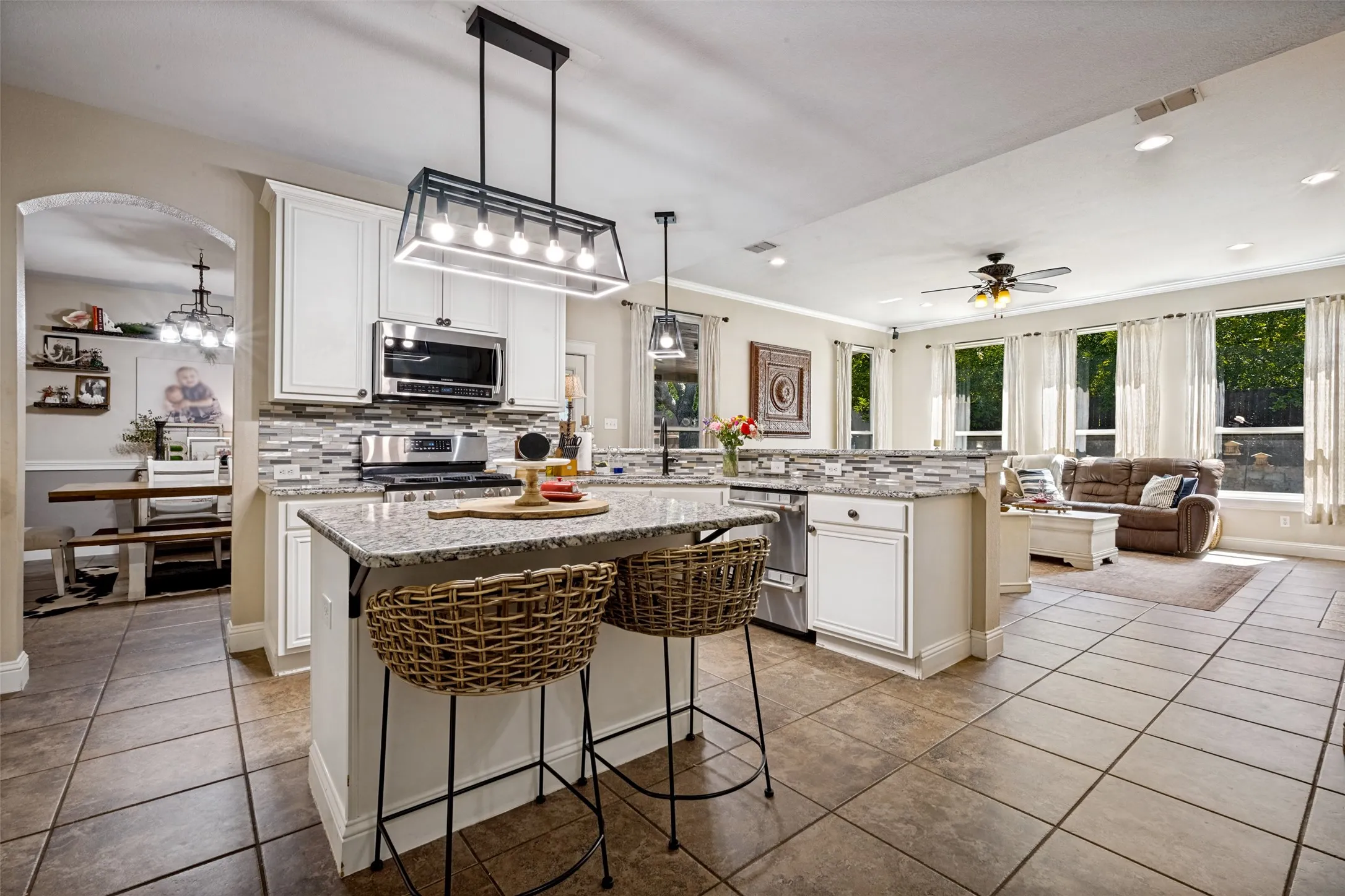 Kitchen featuring white cabinetry, stainless steel appliances, granite countertops, and a mosaic tile backsplash