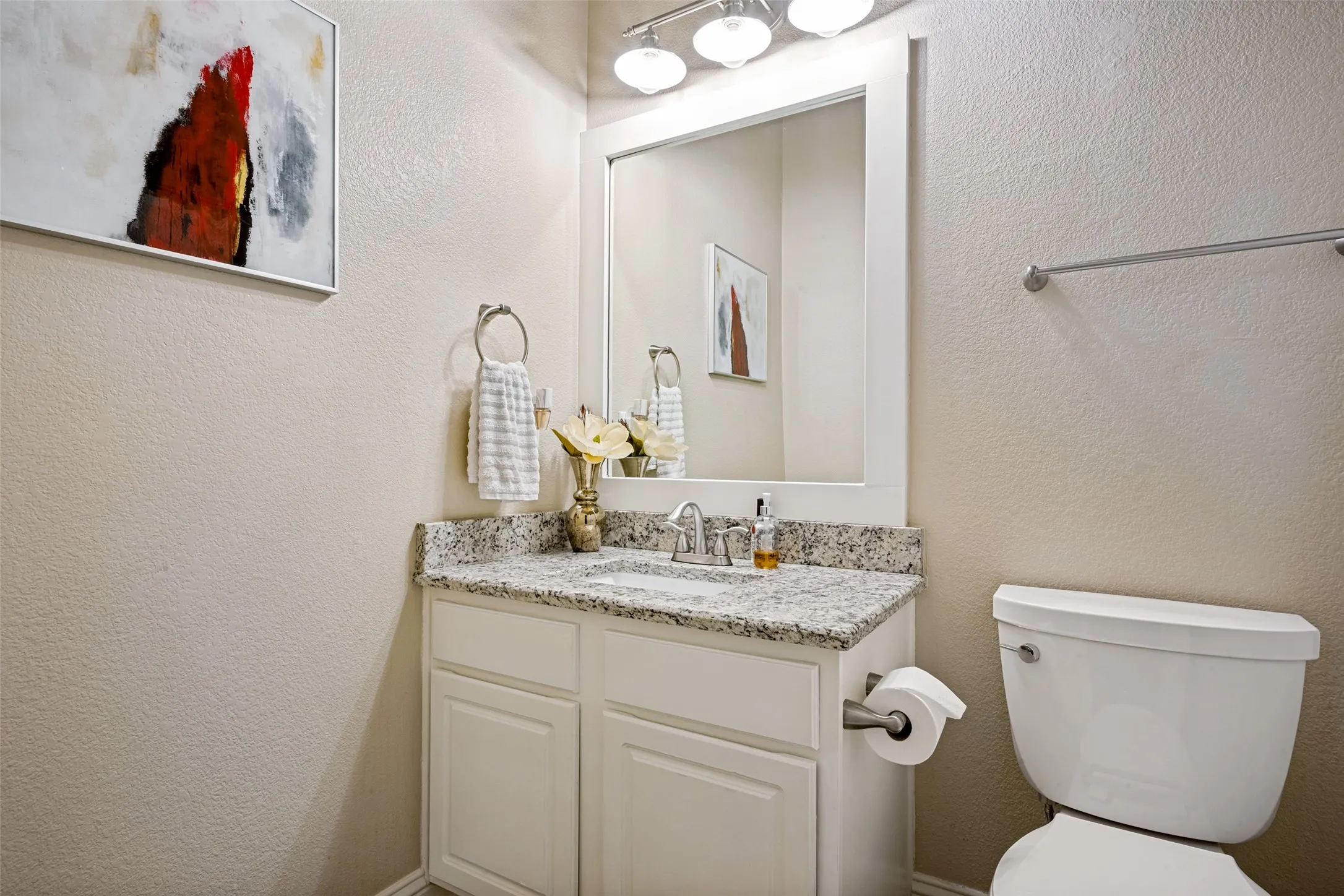 Bathroom vanity featuring a stone countertop, an undermount sink, and a framed mirror with overhead lighting