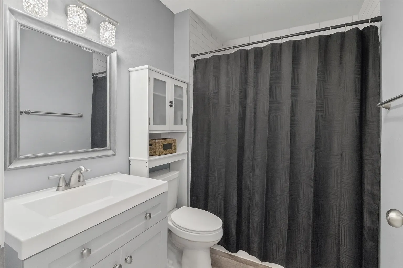 Bathroom featuring a single vanity with integrated sink, brushed nickel faucet, framed mirror, and a three-light vanity fixture