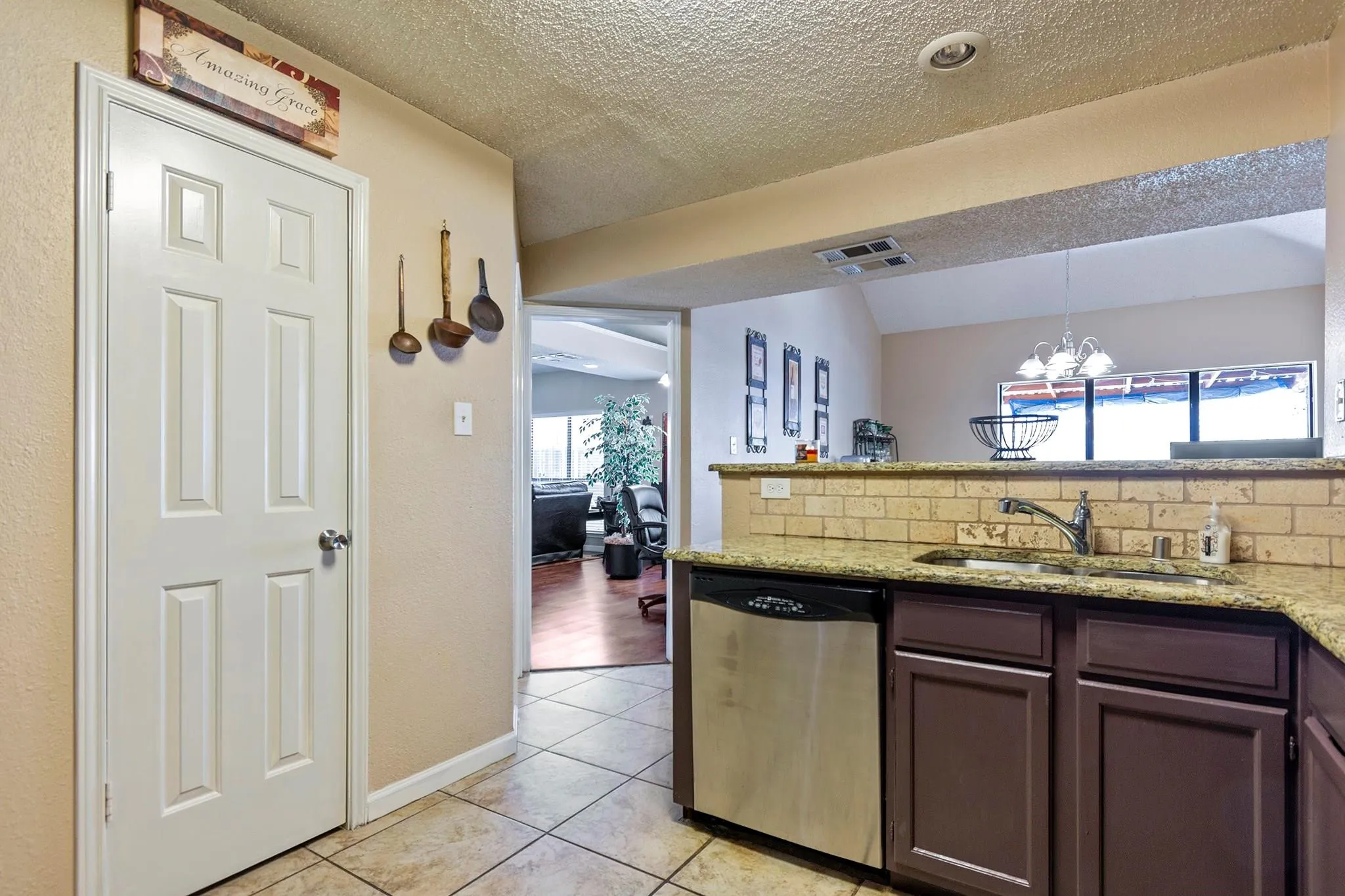 Kitchen featuring an undermount sink, a stainless steel dishwasher, and a stone-look tile backsplash