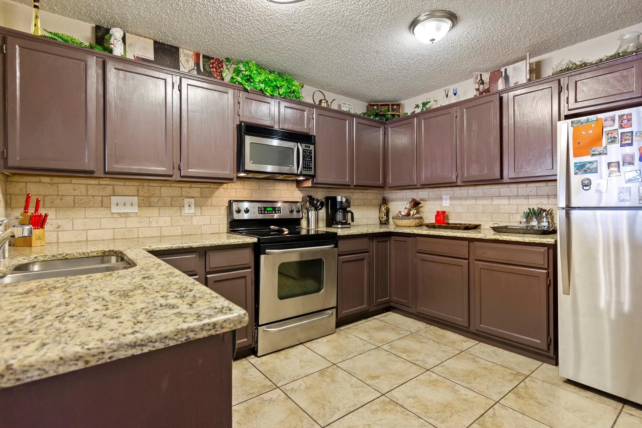 Kitchen featuring brown cabinetry with brushed nickel hardware, light granite countertops, and a subway tile backsplash