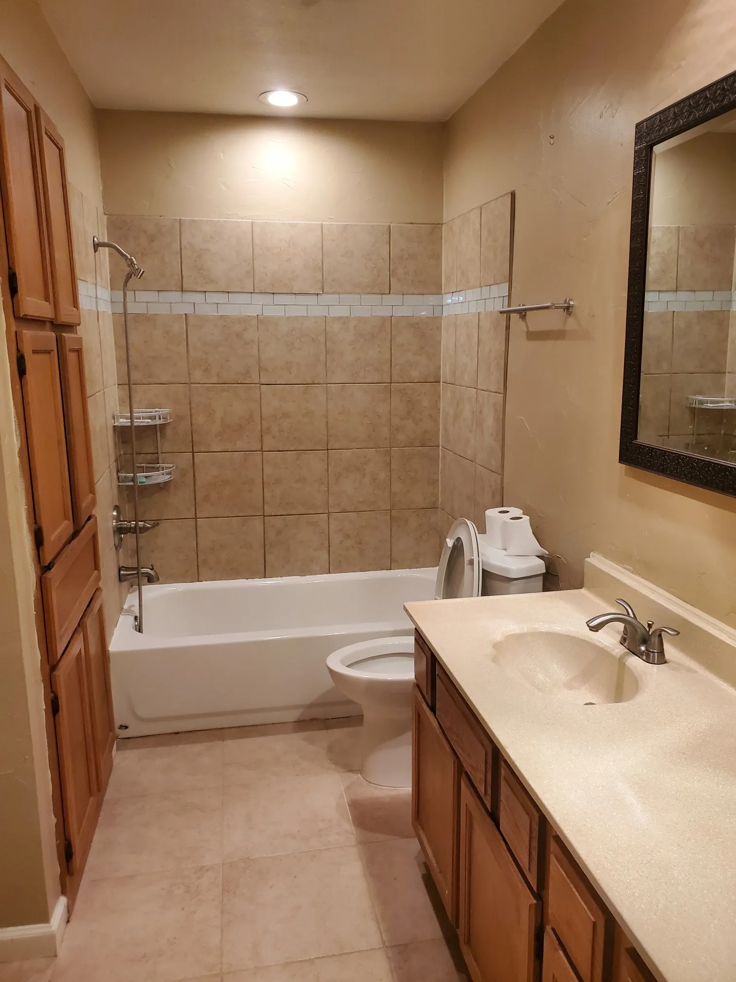 Bathroom featuring a white bathtub, ceramic tile surround with decorative accent band, and recessed lighting
