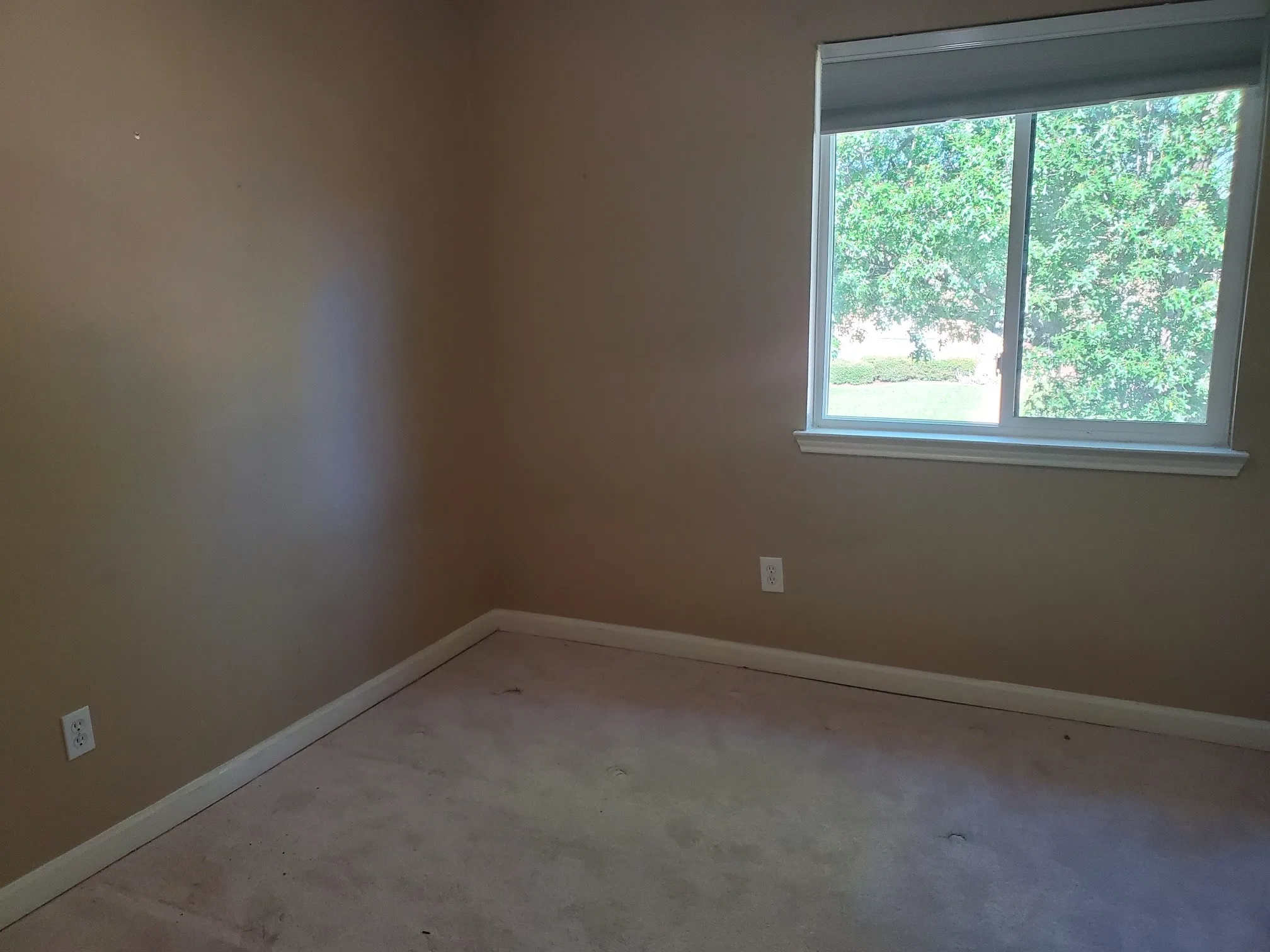 Neutral tone walls with white trim and a single window featuring a white frame