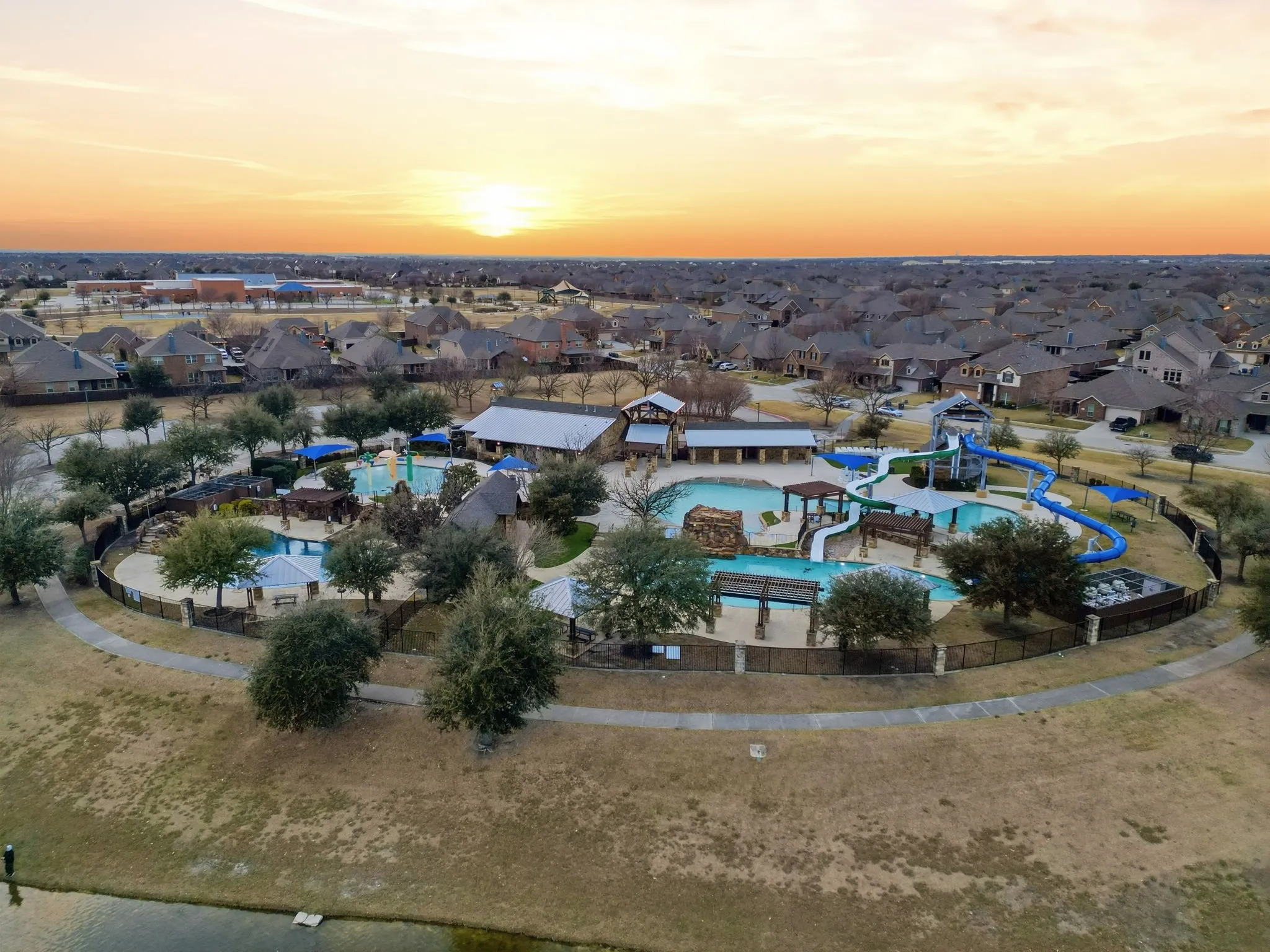 Community recreation area featuring multiple swimming pools, waterslides, and a central clubhouse structure