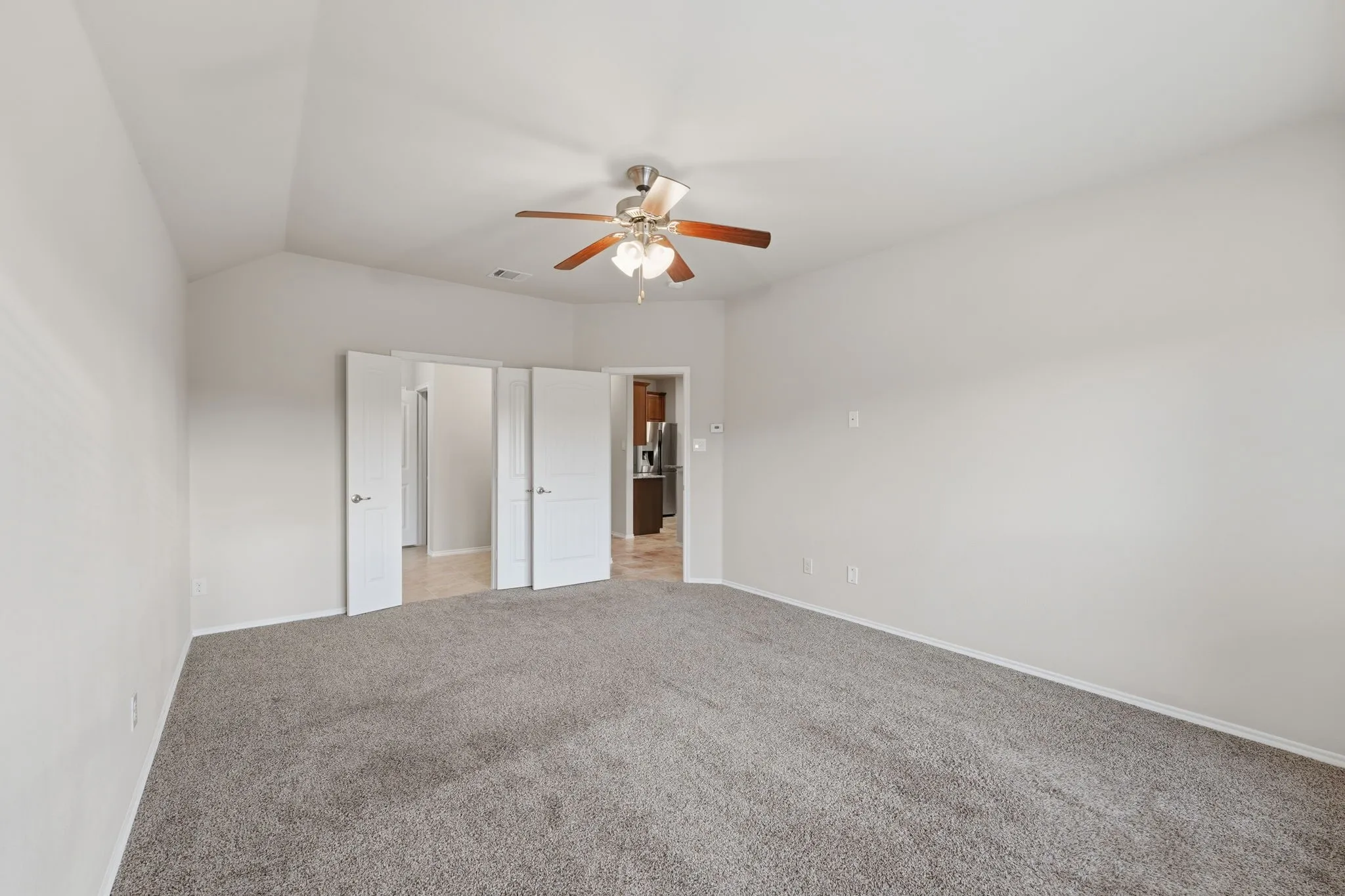 Carpeted interior space featuring a vaulted ceiling and a ceiling fan with light fixture