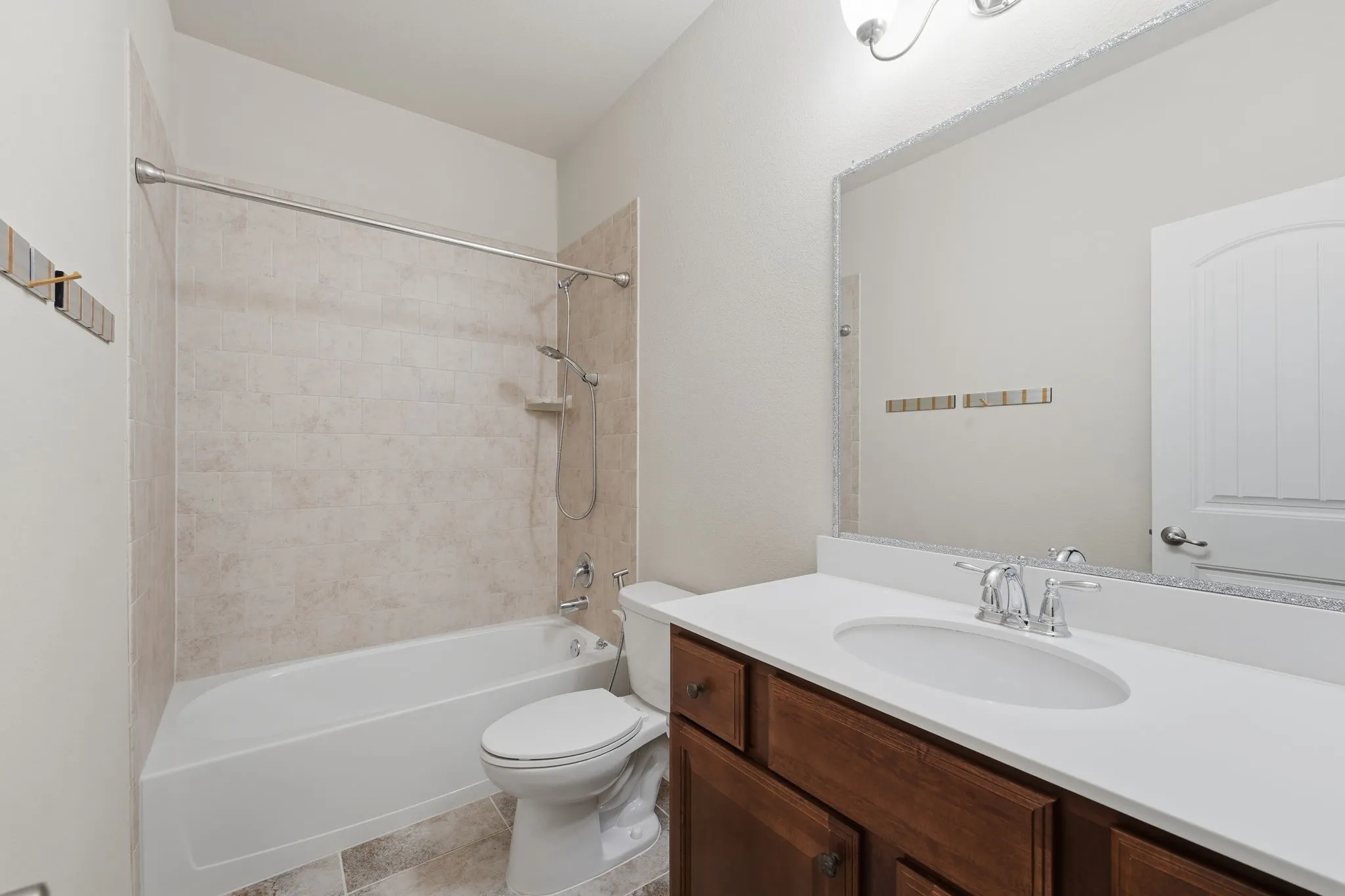 Full bathroom featuring a white tub, light-toned tiled shower surround, dark wood-finish vanity with a white countertop, and a large mirror