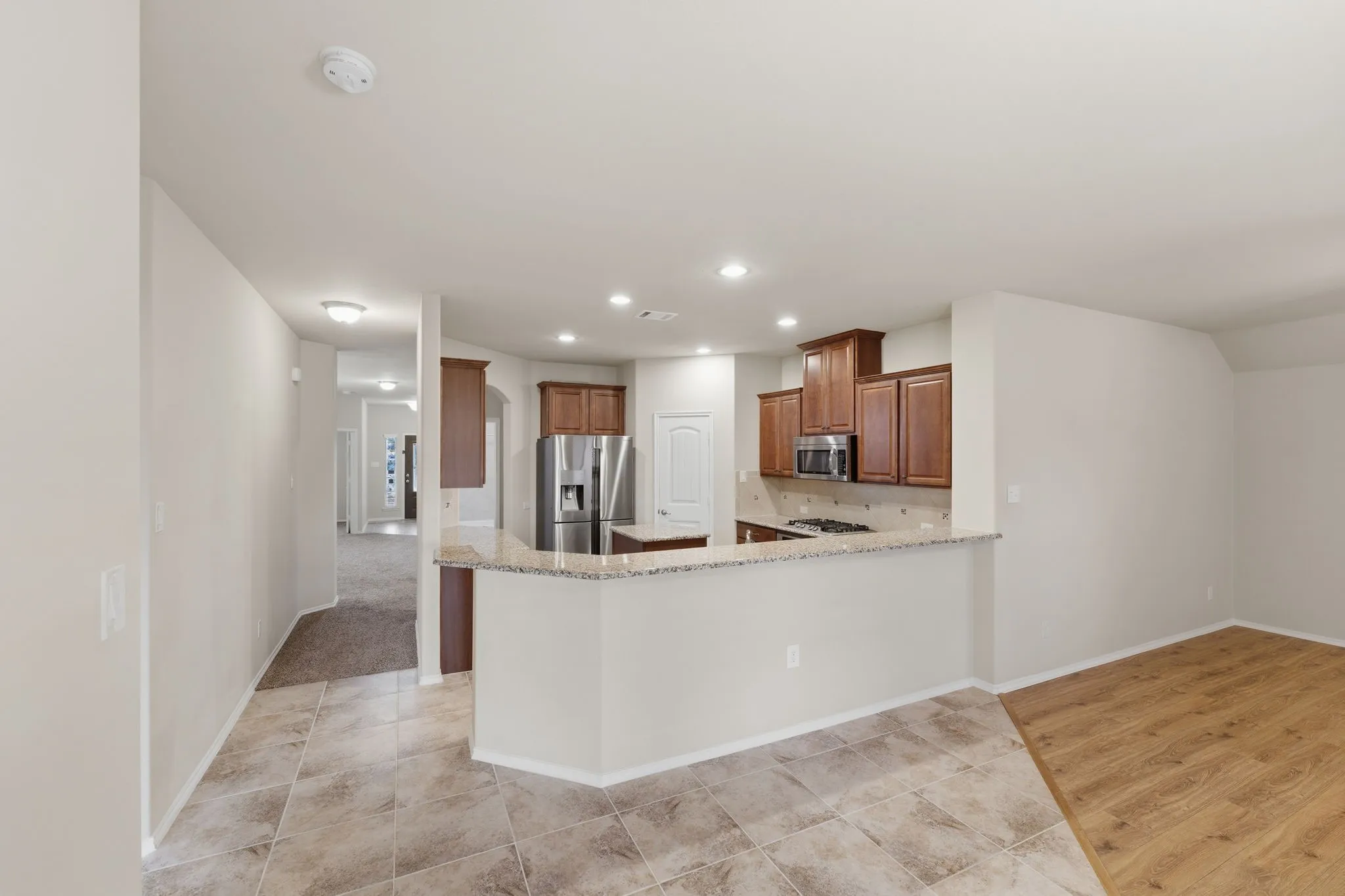 Kitchen featuring wood cabinetry, stainless steel appliances, and a light-toned stone-finish countertop