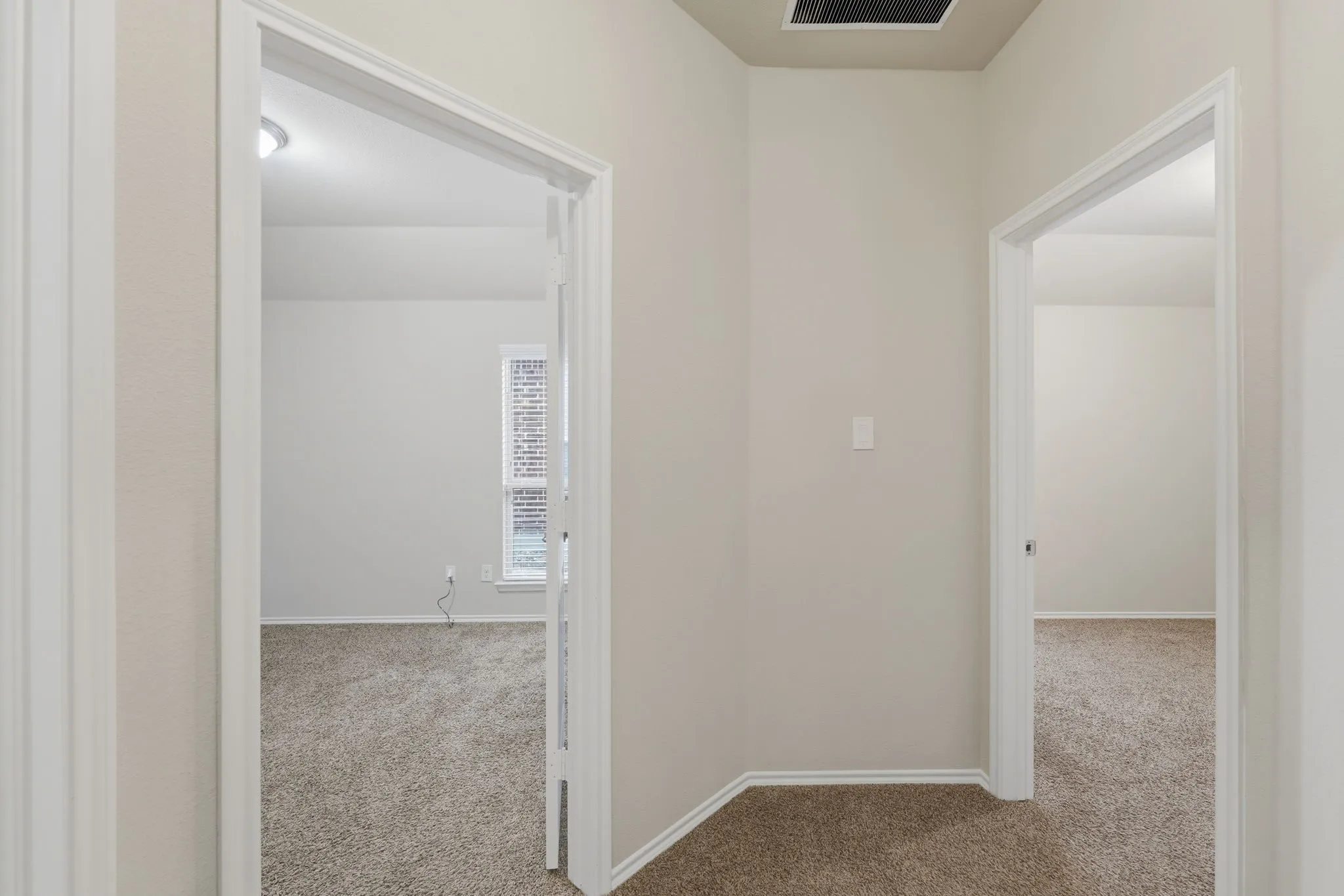 Neutral-toned hallway featuring light beige walls and complementary textured carpeting