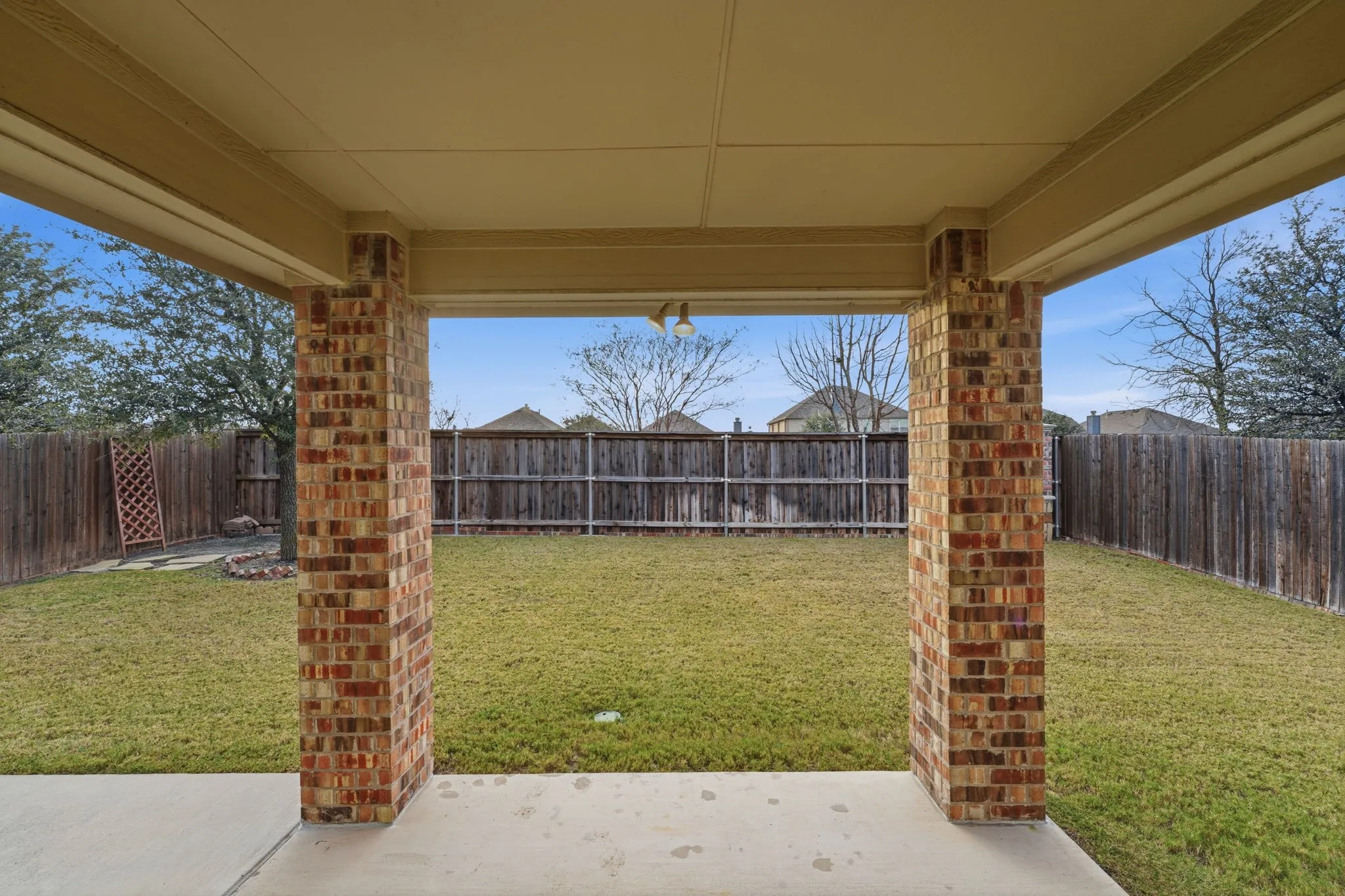 Covered patio with a concrete surface, brick columns, and a ceiling fan