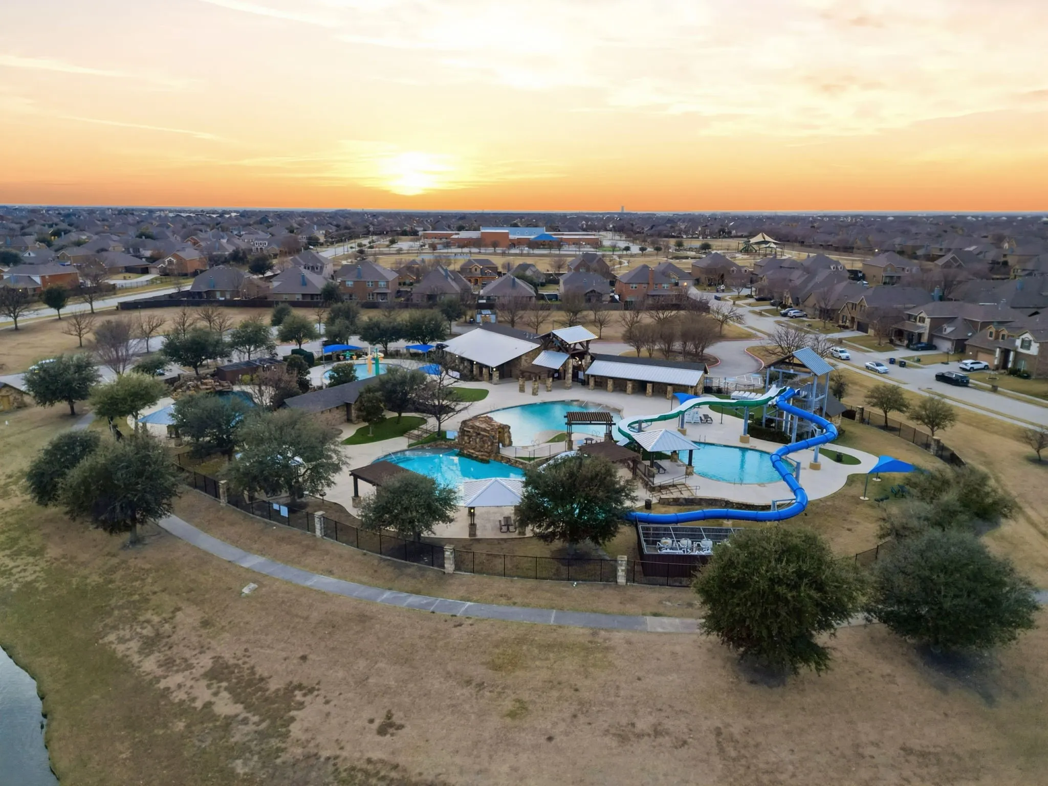 Community recreation area featuring multiple swimming pools, water slides, and covered lounge structures