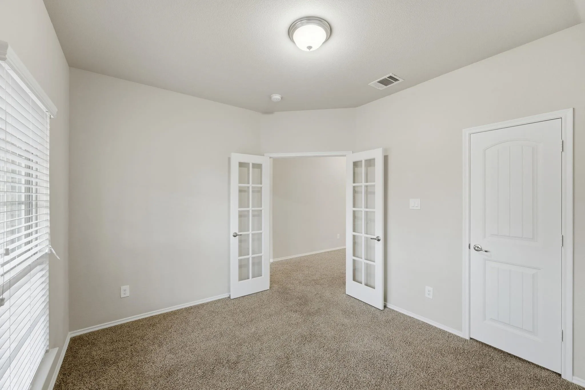 Light-filled room featuring neutral carpet flooring and white painted walls