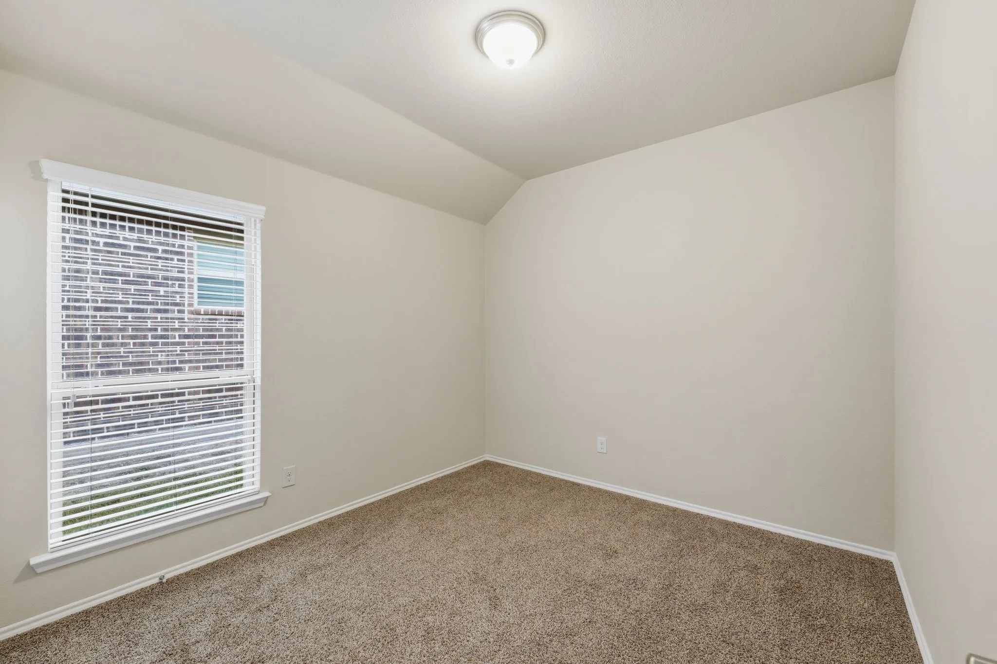 Carpeted room featuring light beige walls, a single window with blinds, and a flush-mount ceiling light fixture