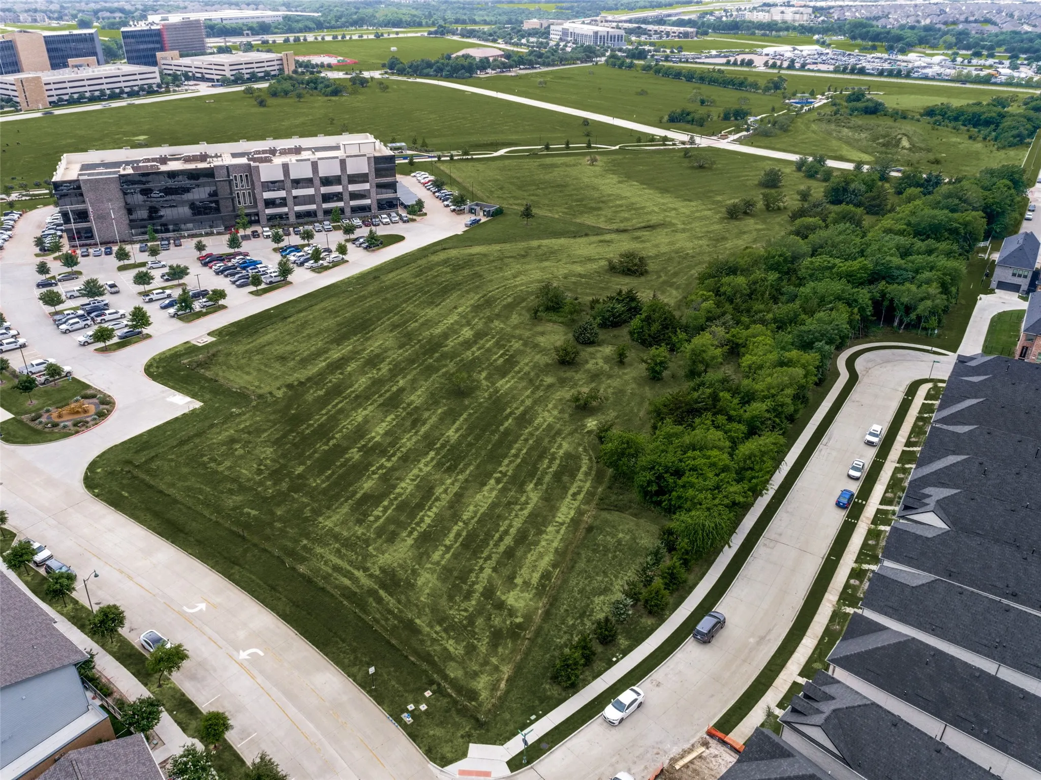 Expansive undeveloped parcel featuring established green space, a mature tree line, and paved road frontage
