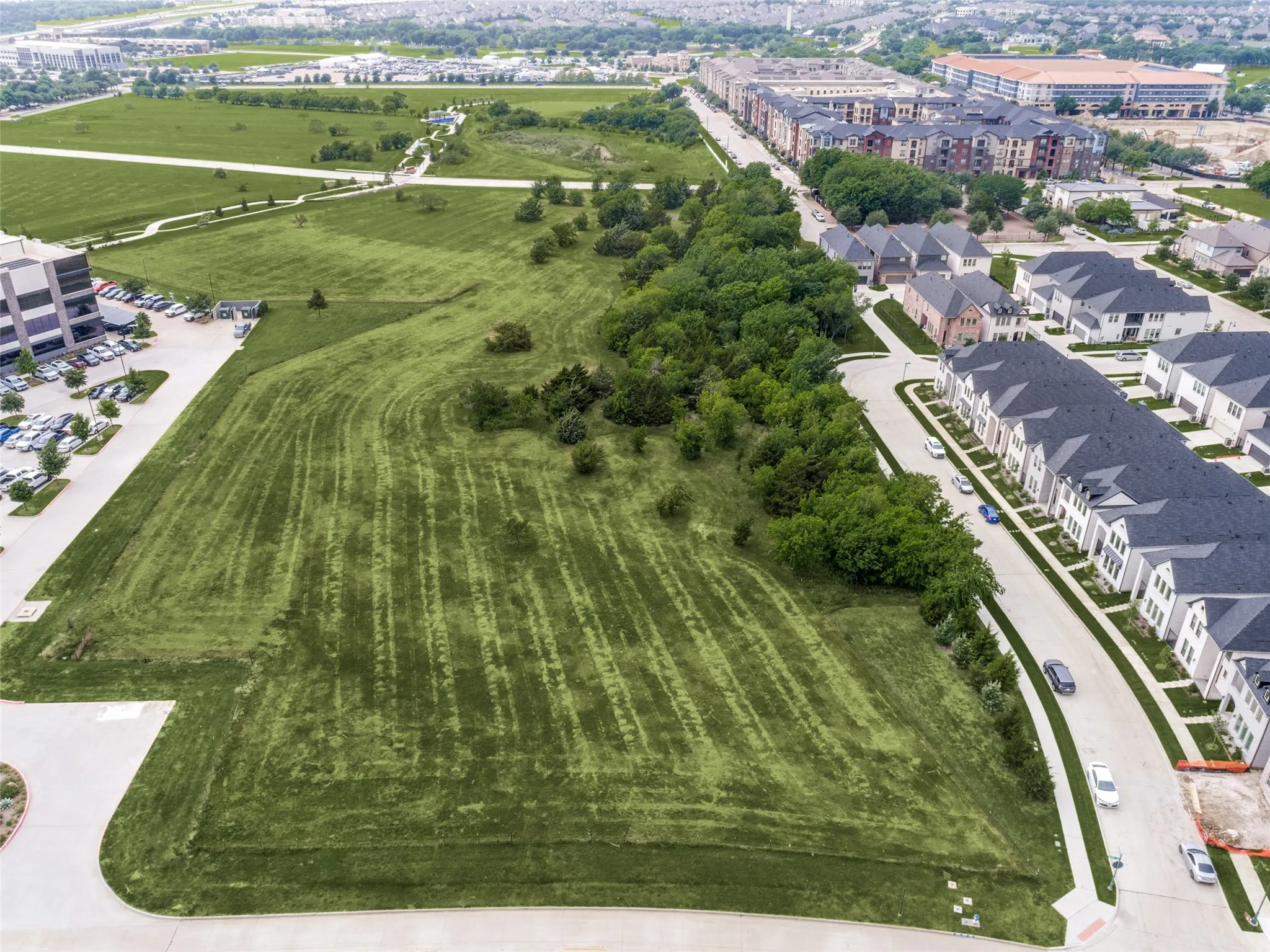 Expansive land parcel featuring manicured green space, mature trees, and direct road frontage