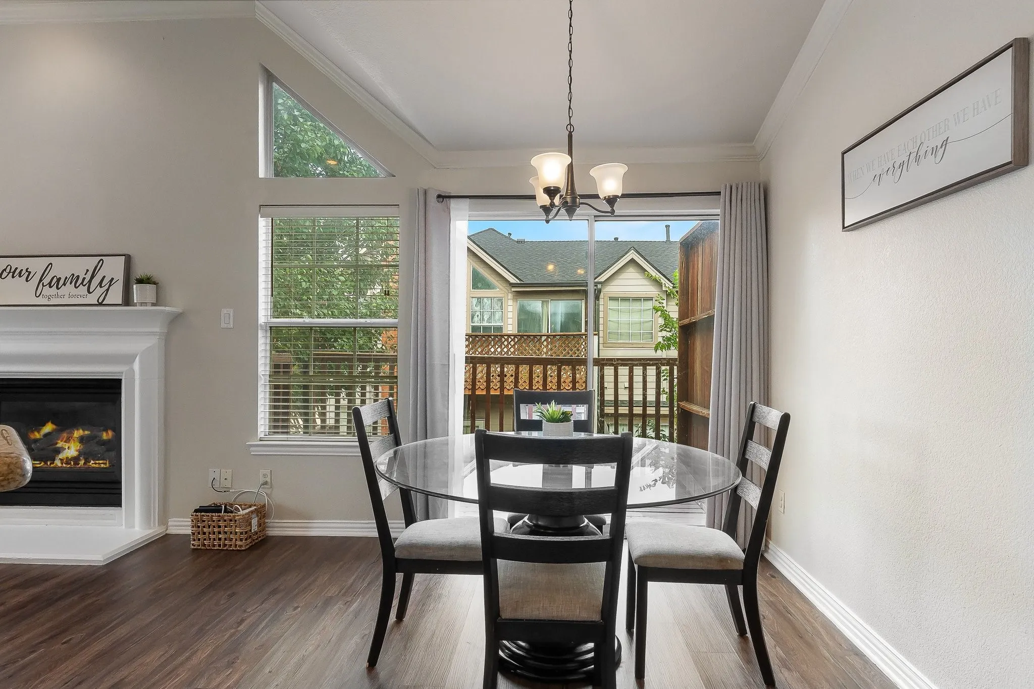 Dining area with wood-finish flooring, a fireplace featuring a white mantel, and vaulted ceilings with a triangular window
