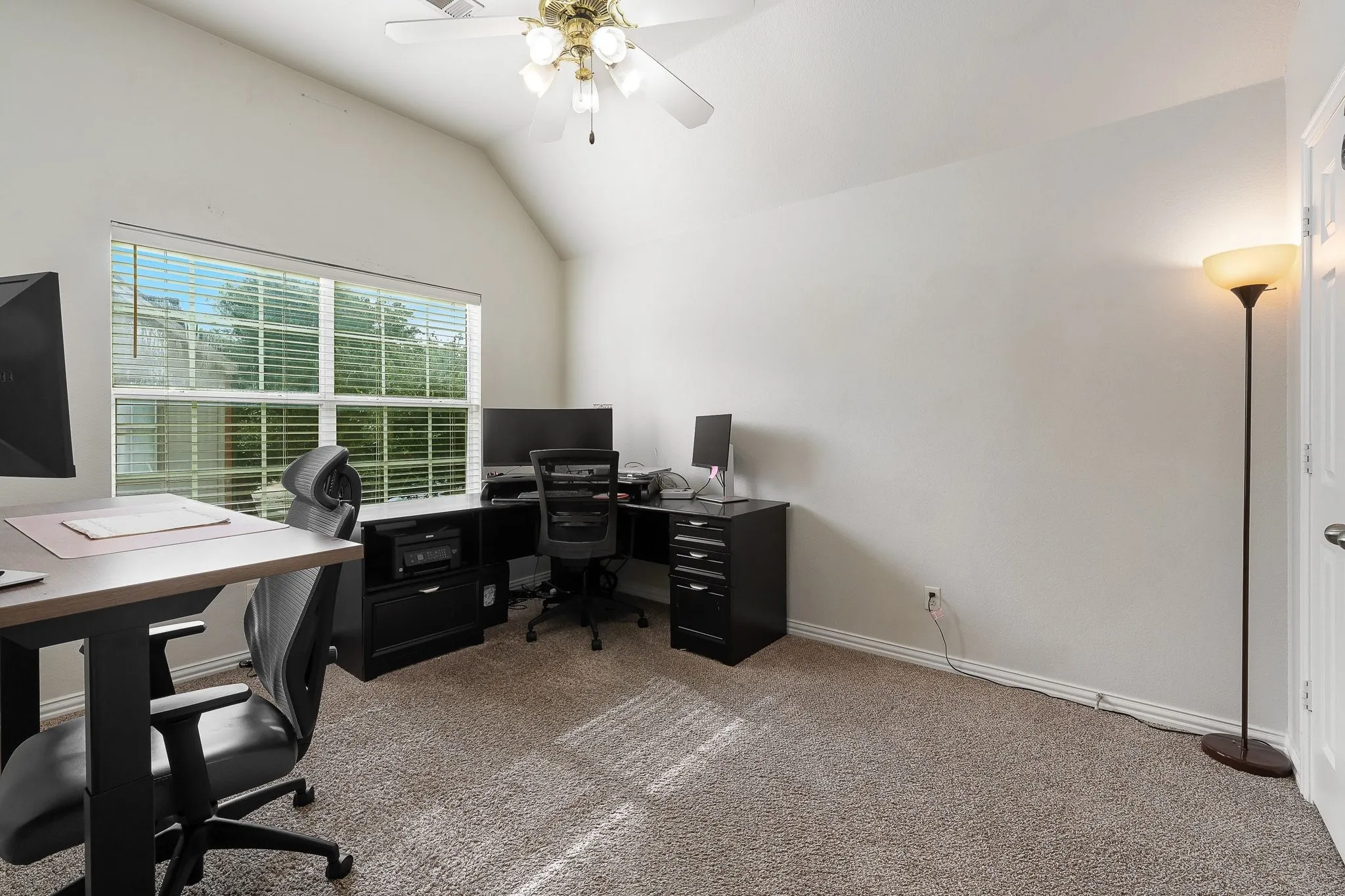 Carpeted interior space featuring a vaulted ceiling and a ceiling fan with integrated lighting