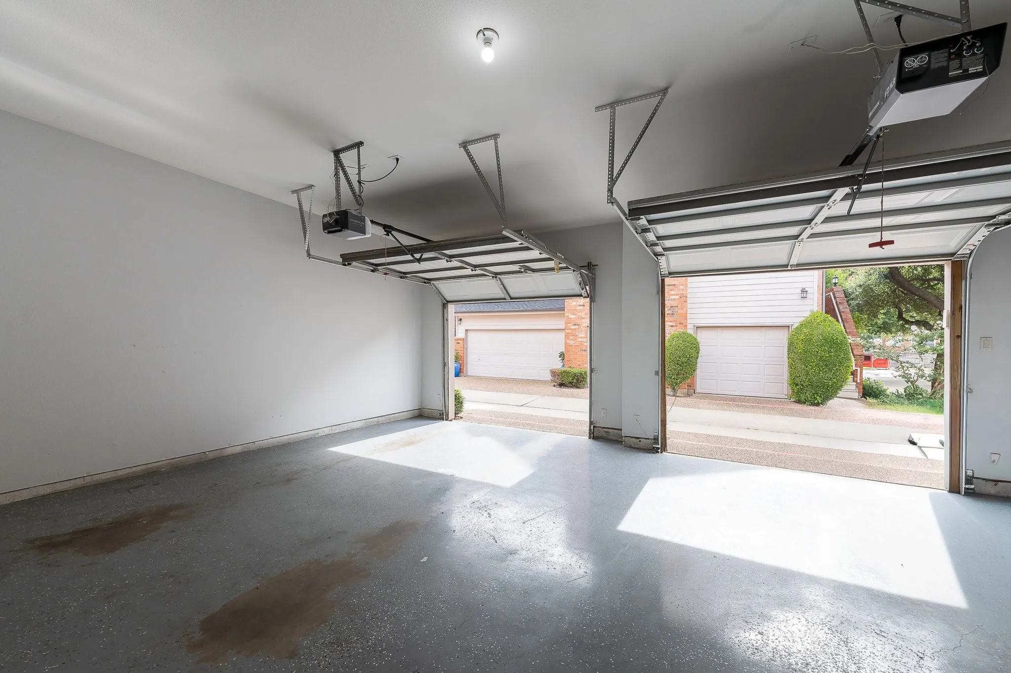Two-car garage featuring a painted concrete floor, white walls, and two overhead garage door openers
