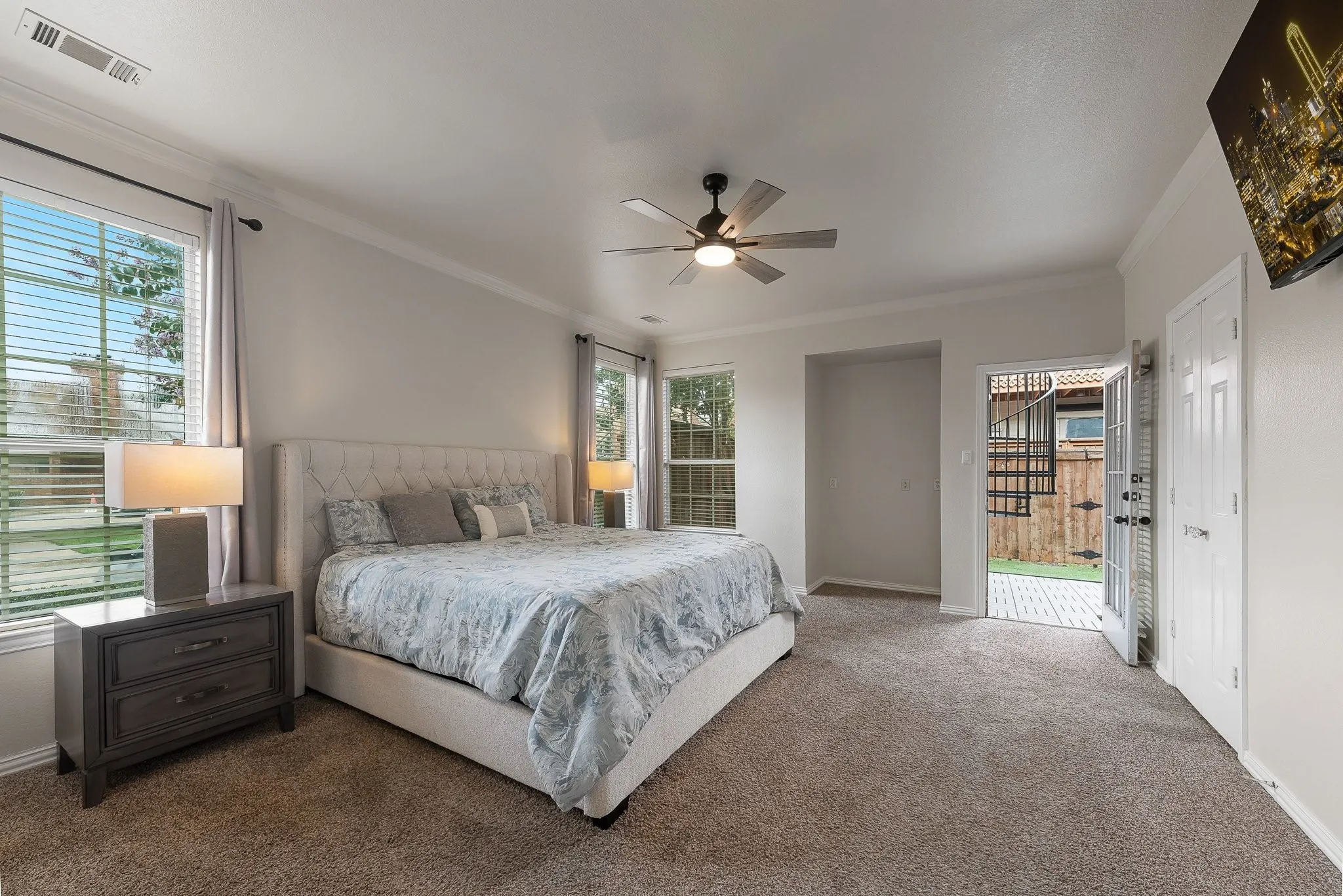 Spacious bedroom featuring plush carpeting, crown molding, and a ceiling fan with integrated lighting