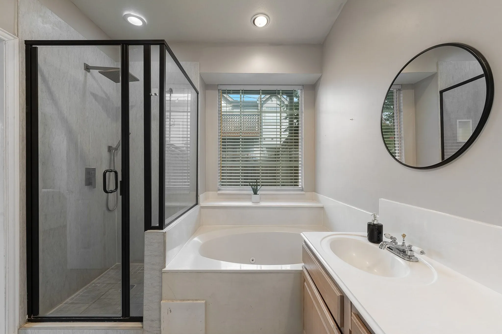 Bathroom featuring a walk-in shower with black-framed glass enclosure, a built-in soaking tub, and a single vanity with an integrated sink