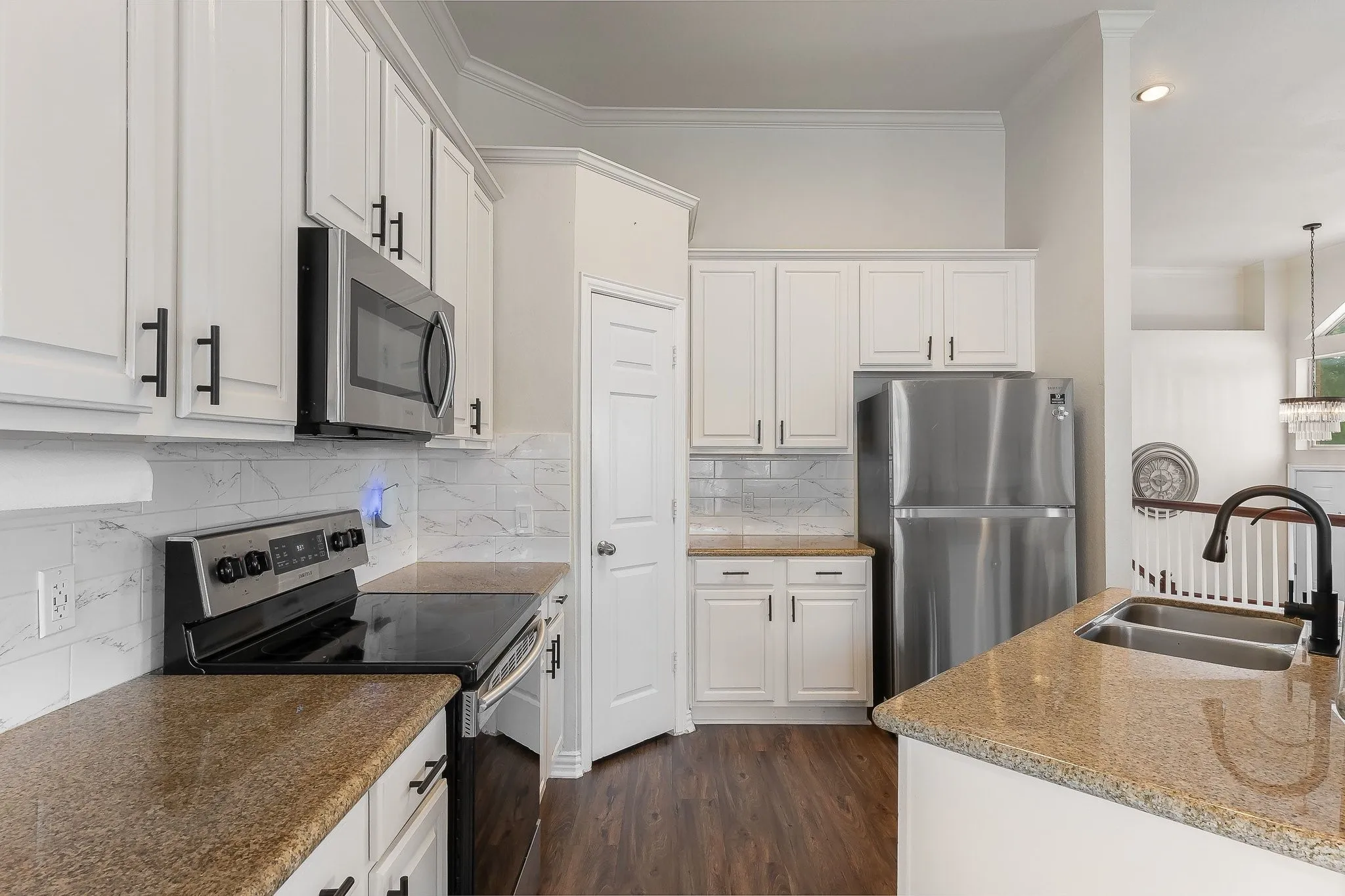 Modern kitchen featuring white cabinetry with matte black hardware, stainless steel appliances, and a double basin sink
