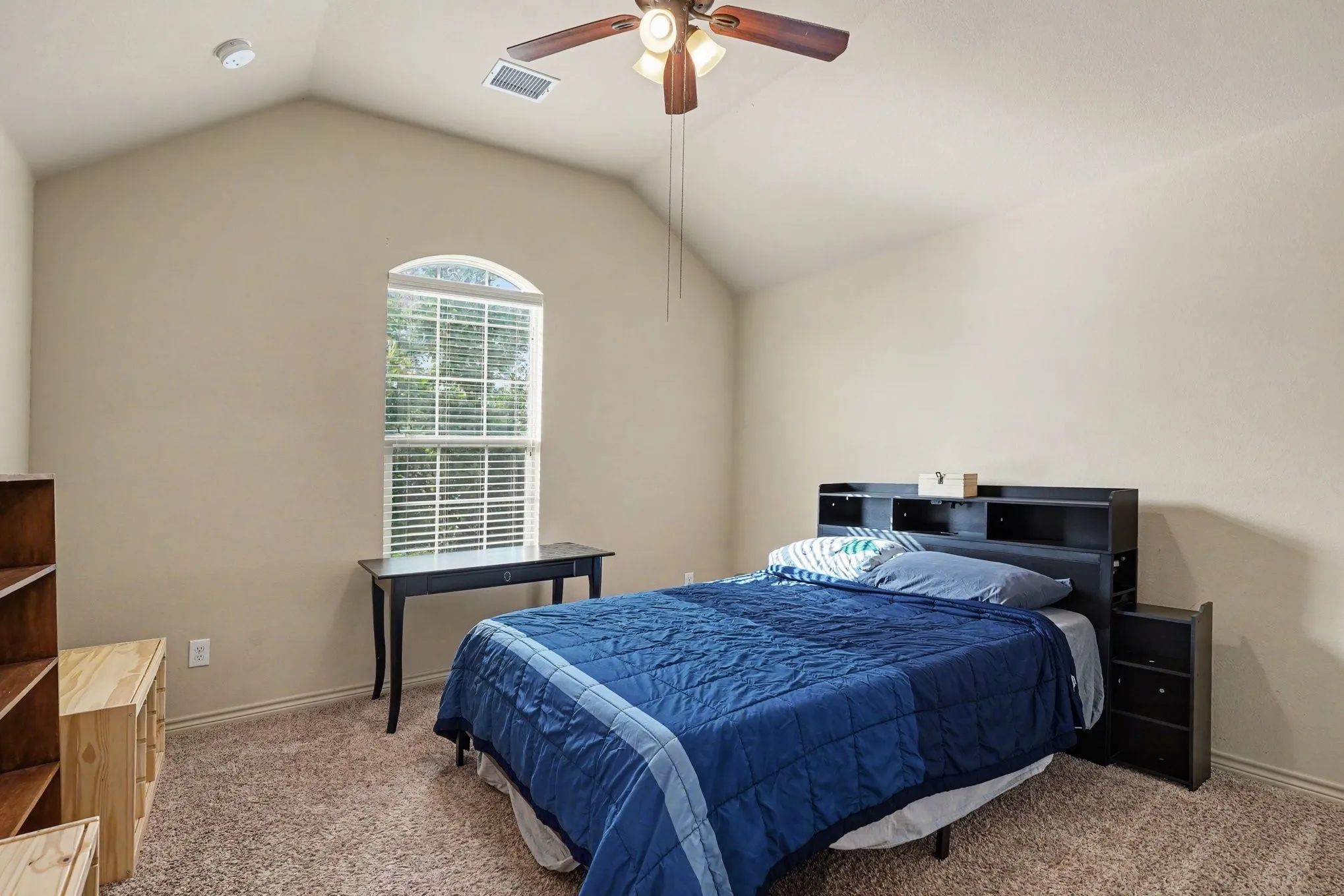 Vaulted ceiling bedroom featuring an arched window with blinds, carpet flooring, and a ceiling fan with light fixture